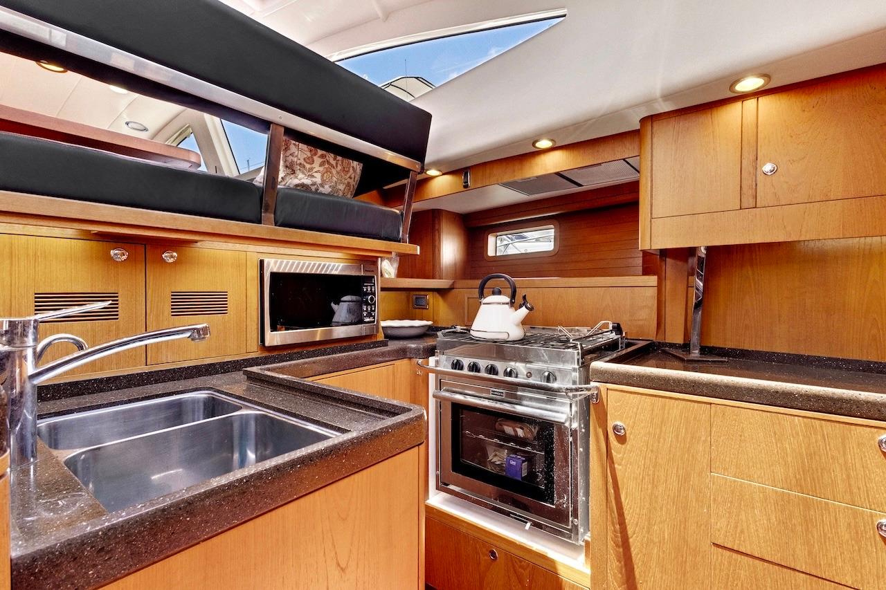 Luxurious 2011 Southerly 57 RS yacht kitchen with modern appliances and sleek wood cabinetry.