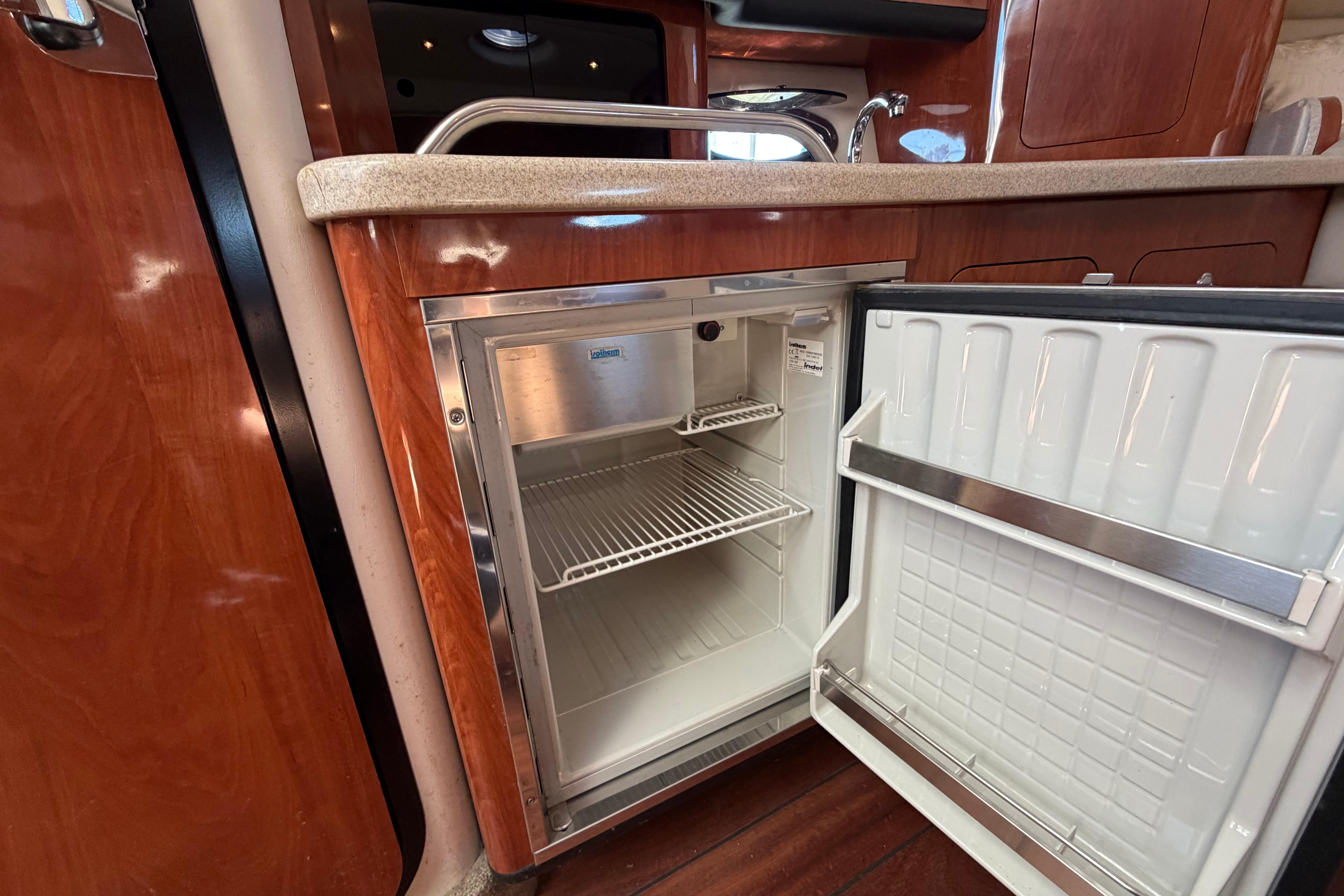2008 Crownline 340 CR yacht interior with open mini fridge and wooden cabinetry.