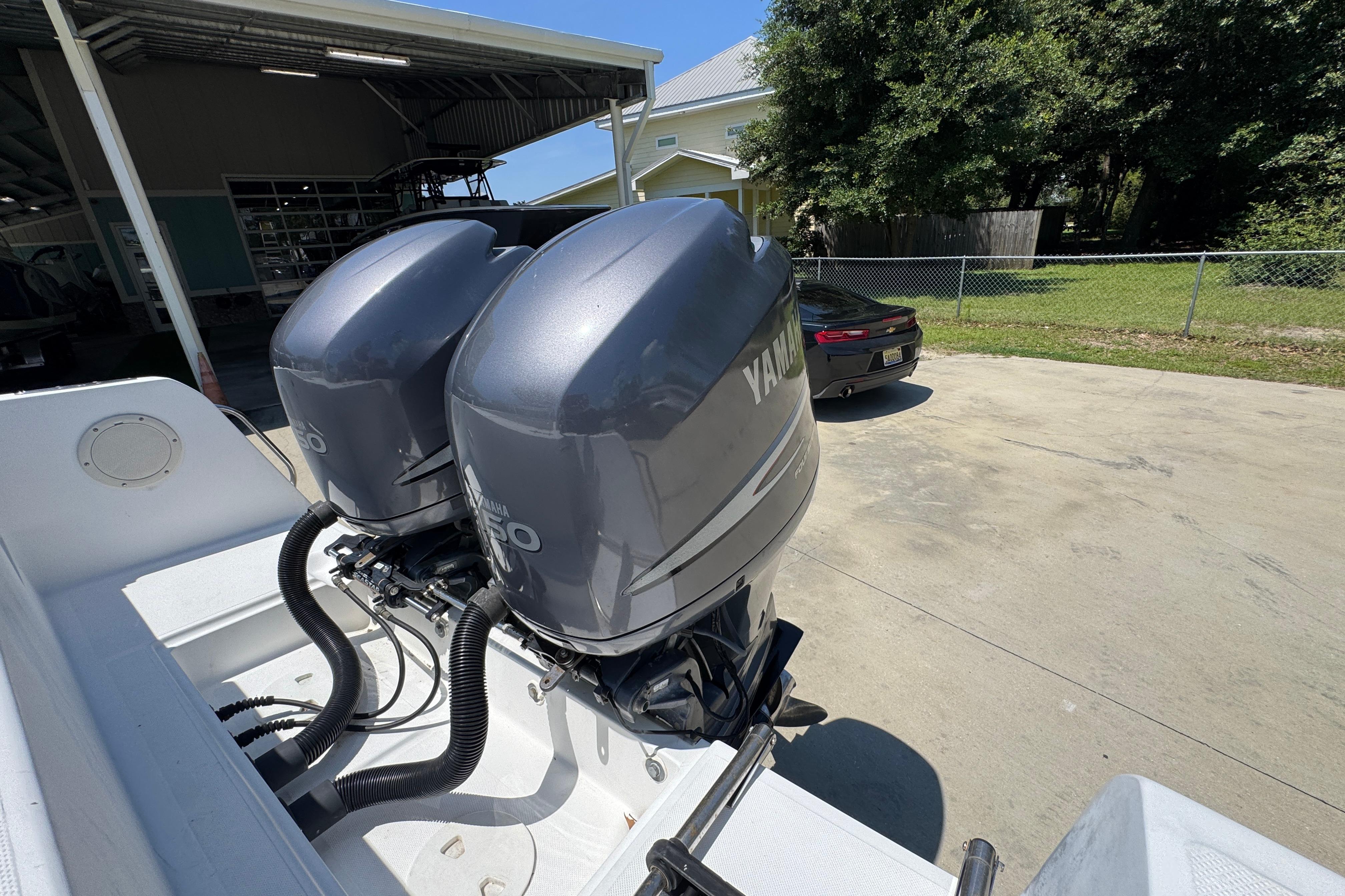 Twin Yamaha outboard engines on a 2000 Stamas 250 Tarpon boat, parked outdoors.