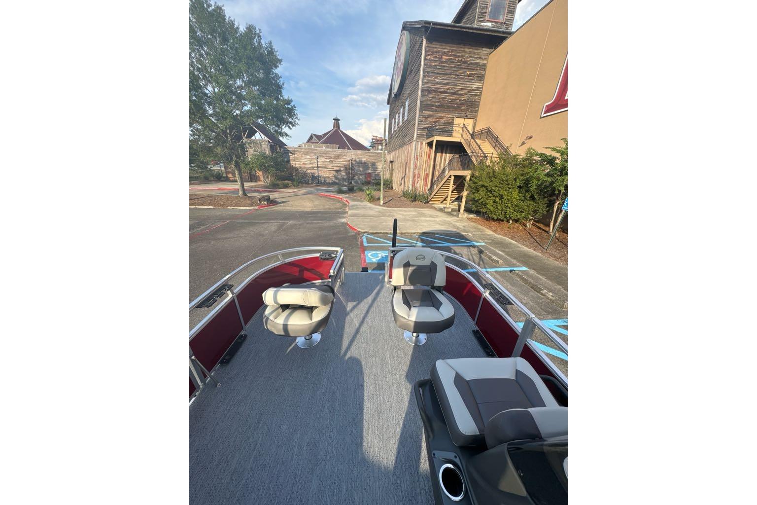 2026 Sun Tracker Bass Buggy 16 XL Select pontoon boat with seating, parked outdoors.