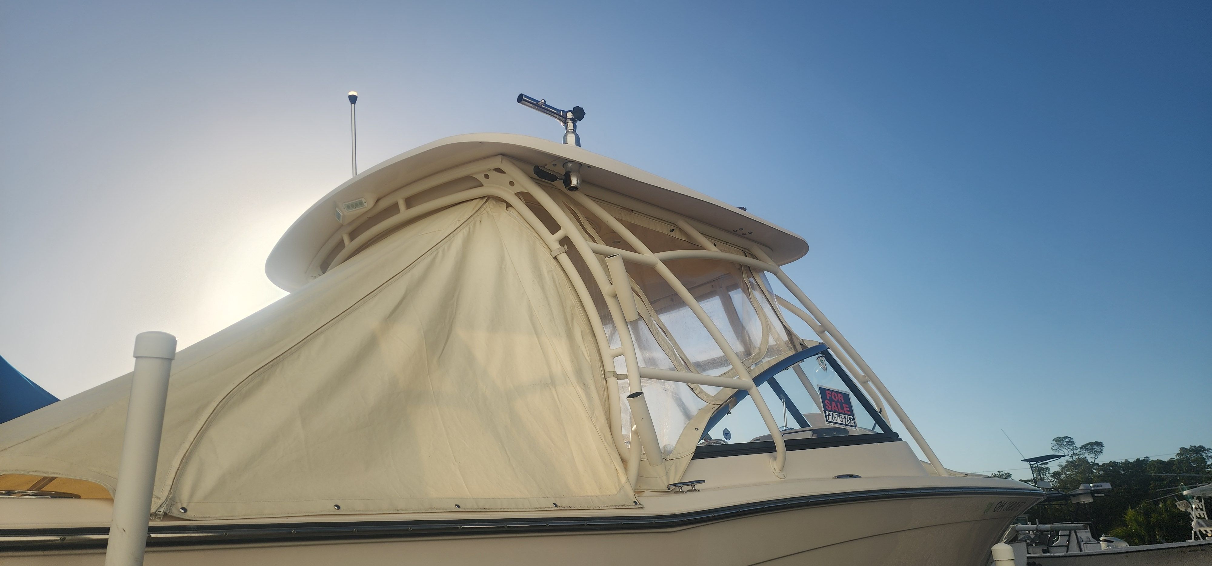 A 2015 Grady-White Freedom 275 boat with an enclosed canopy, glistening in the sunlight.