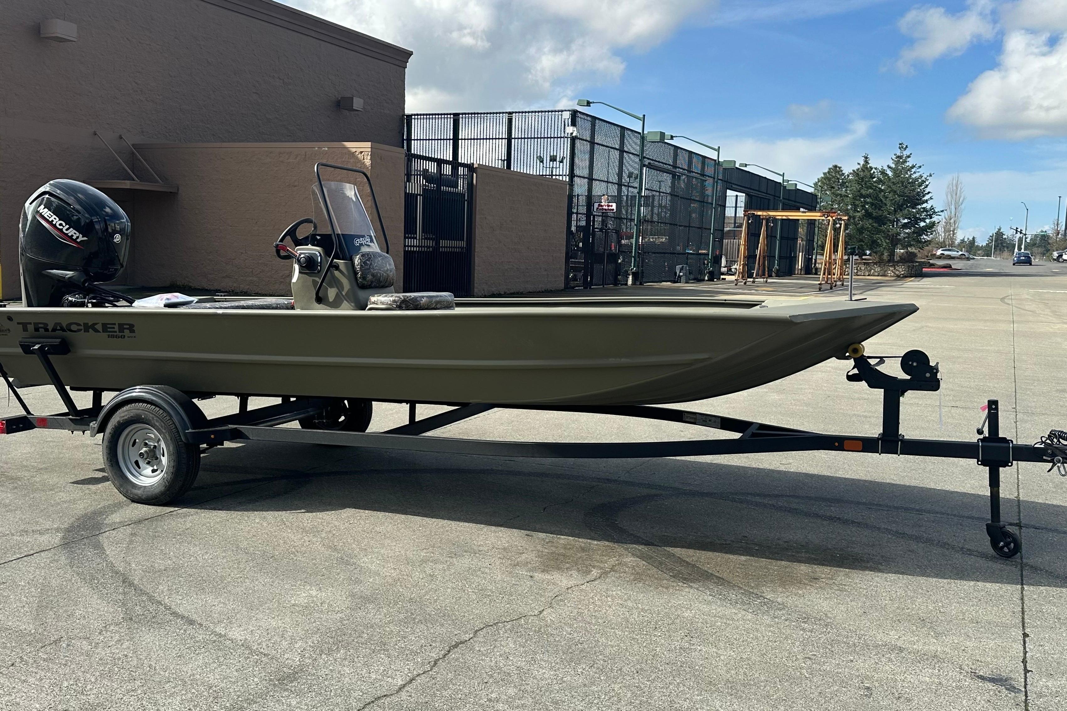 2026 Tracker Grizzly 1860 CC boat on trailer, parked outdoors under a cloudy sky.