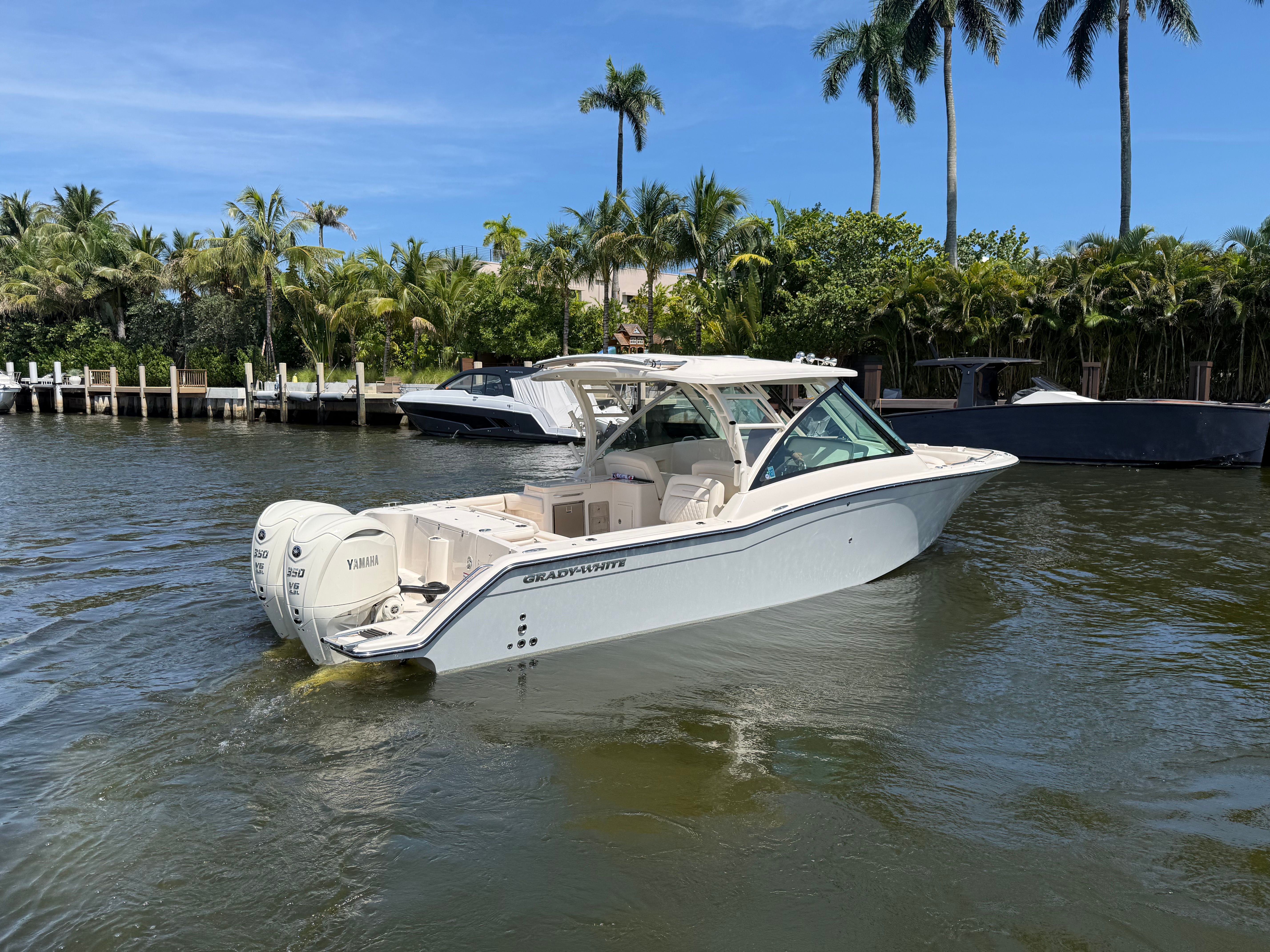 Grady-White Freedom 325 on calm water, surrounded by palm trees and other boats.