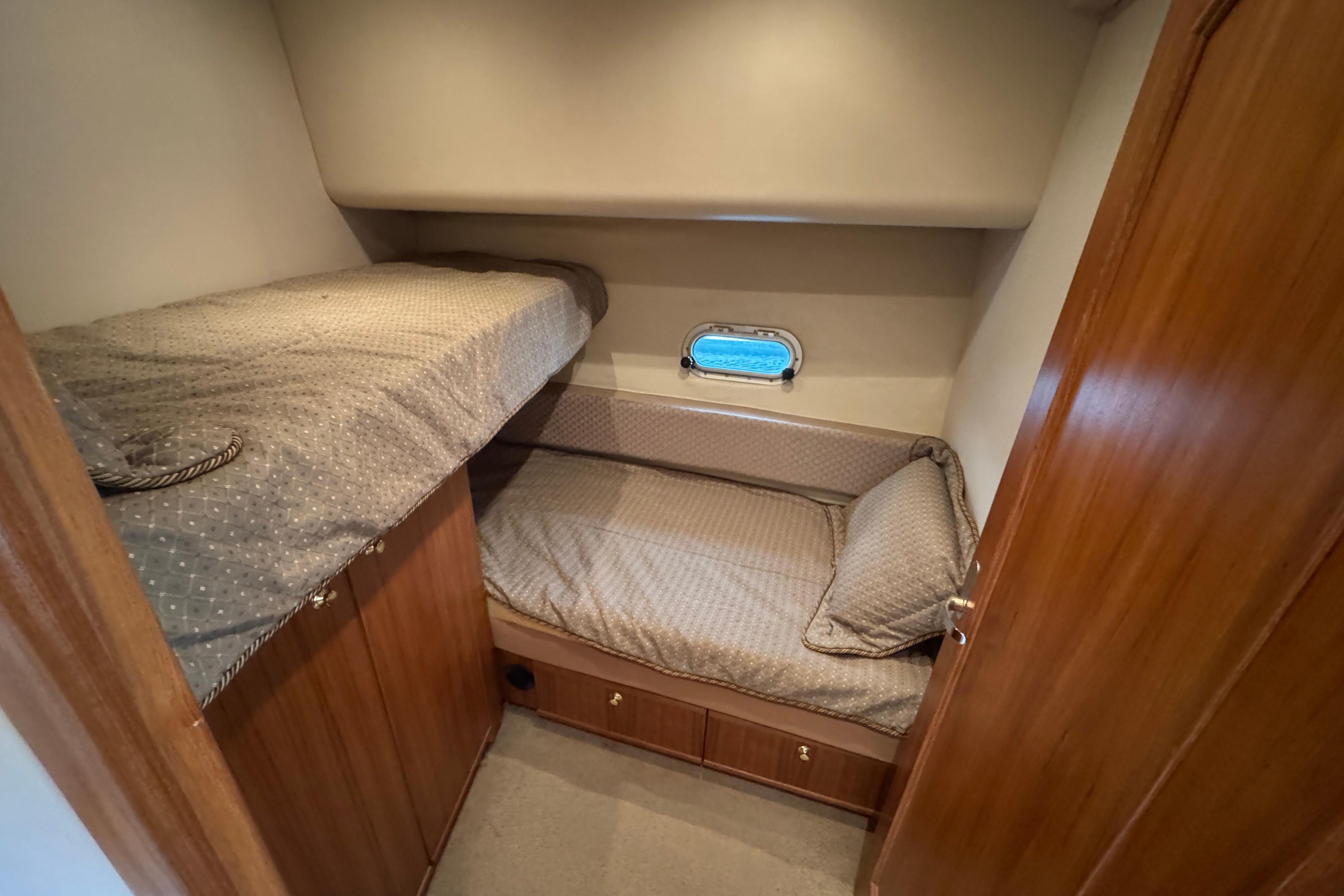 1998 Bayliner 5788 Pilot House Motoryacht cabin with bunk beds and porthole window.