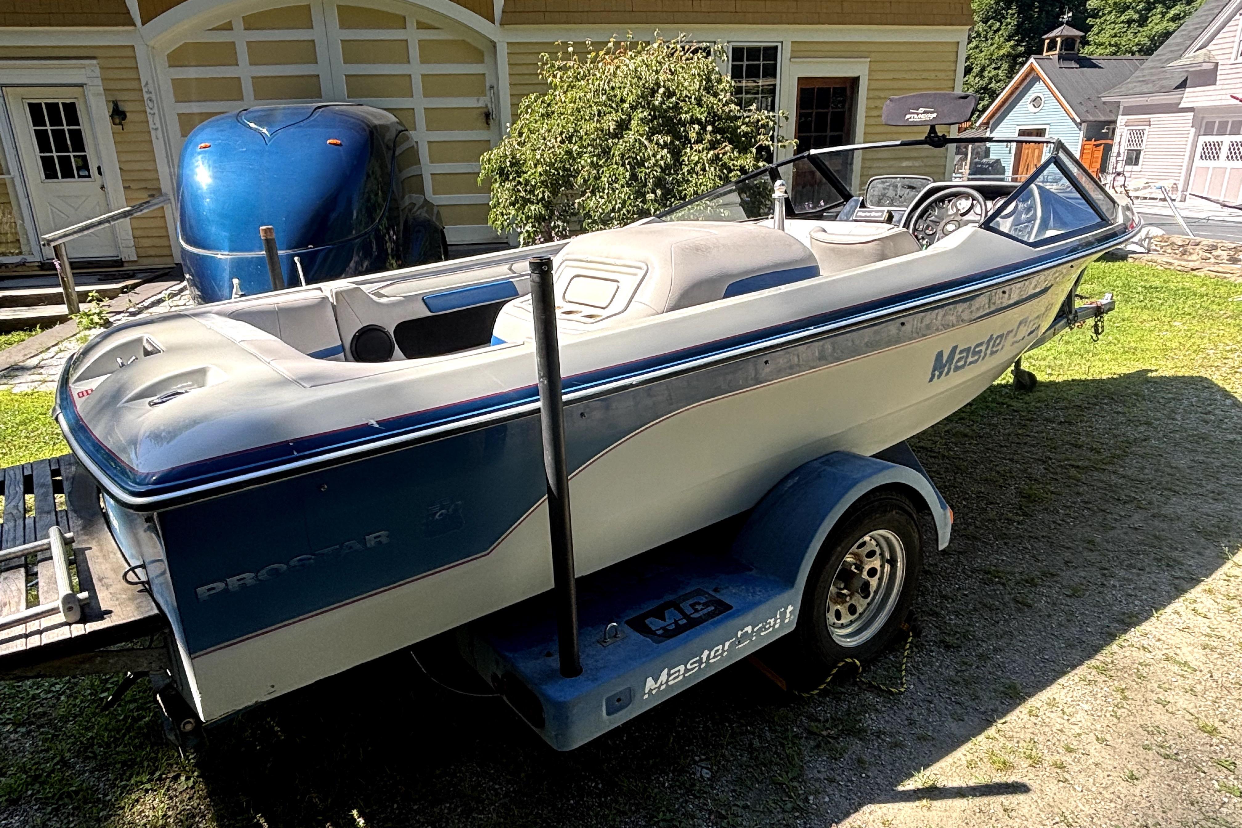 1990 MasterCraft ProStar 190 boat on trailer, parked in a sunny yard.