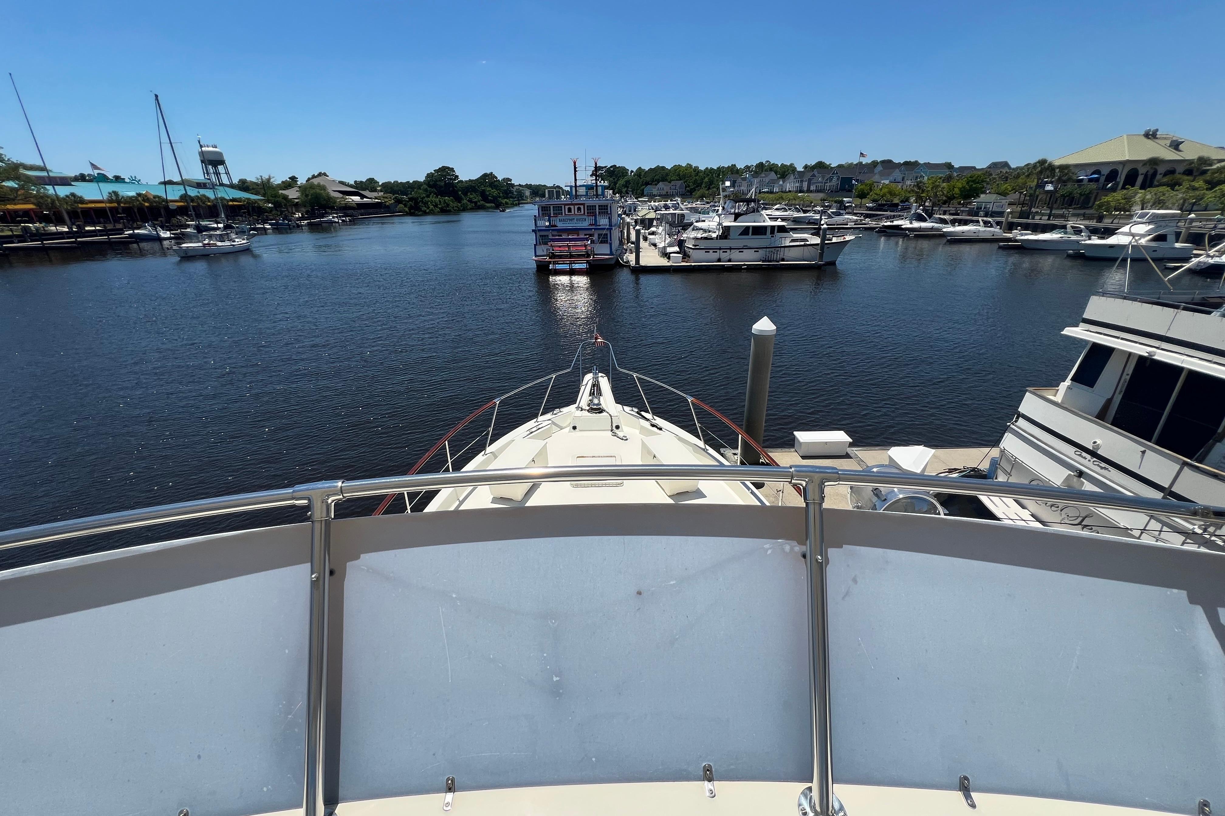 1987 Hatteras 70 Cockpit Motor Yacht docked in a scenic marina under clear blue skies.