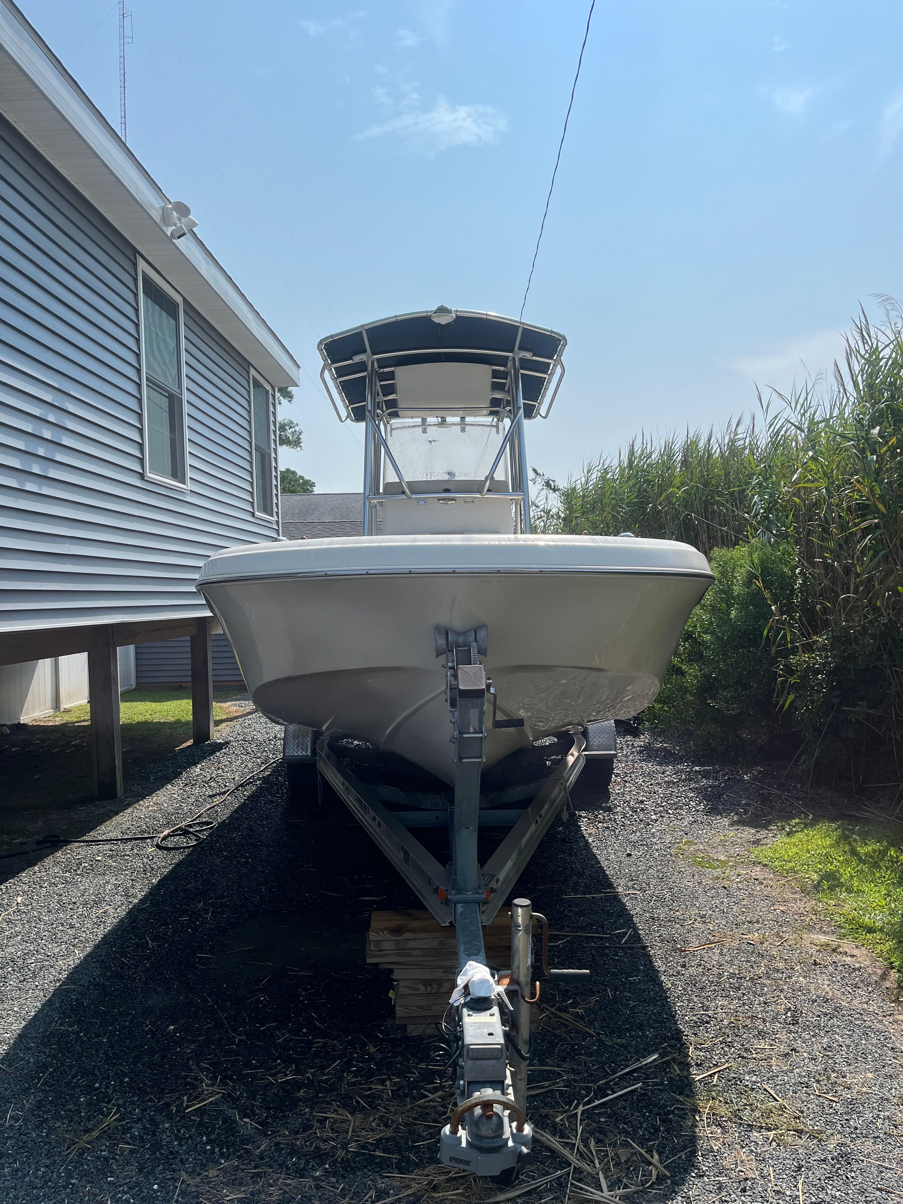 2014 Carolina Skiff 23 Ultra Elite on trailer beside house.