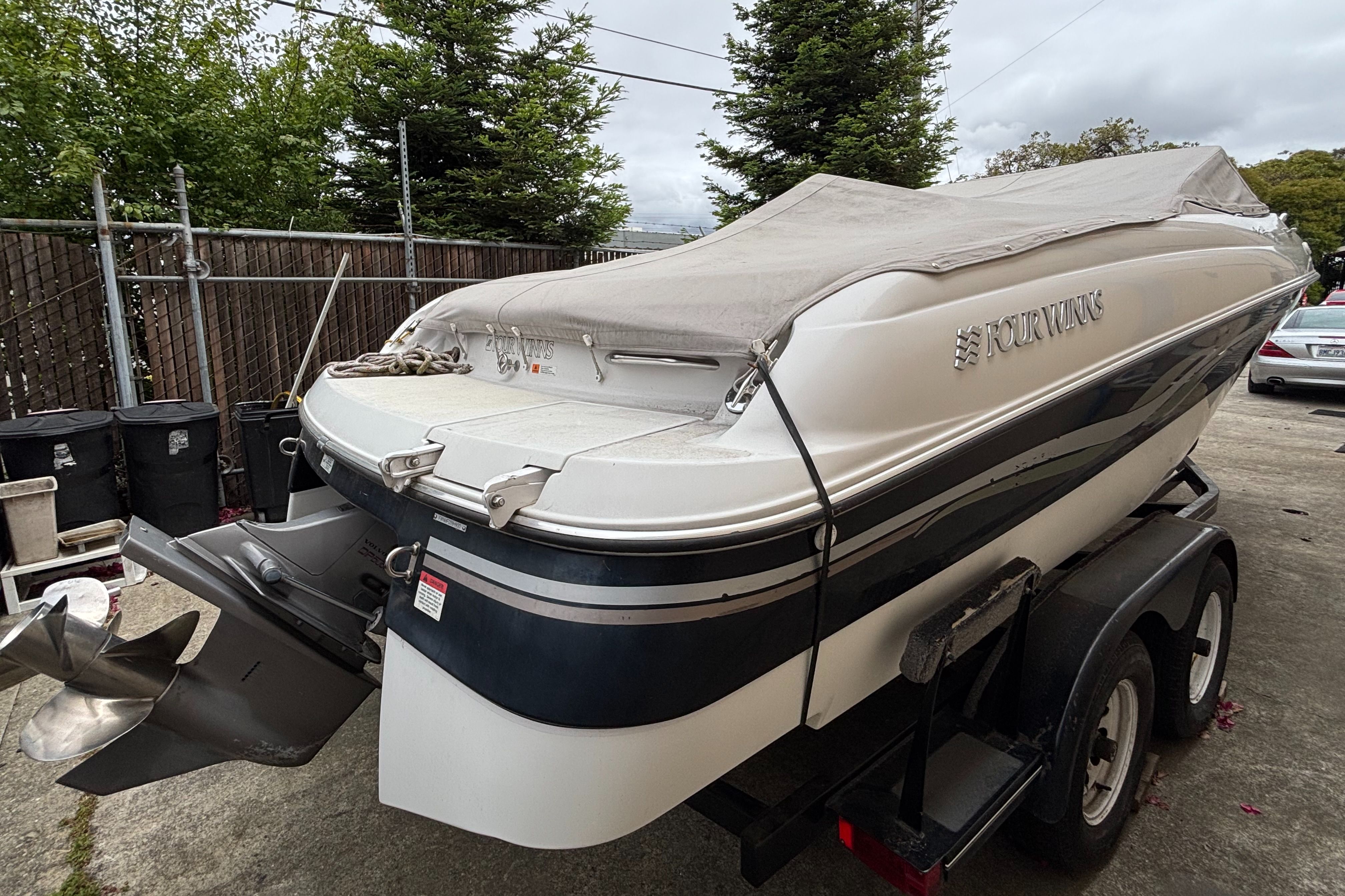 A 2000 Four Winns 220 Horizon boat on a trailer, with a cover and outboard motor.