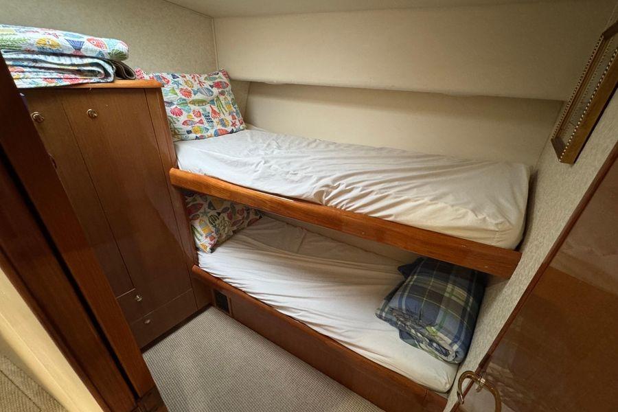 Bunk beds in 2002 Viking 61 Enclosed Bridge yacht cabin with colorful bedding.