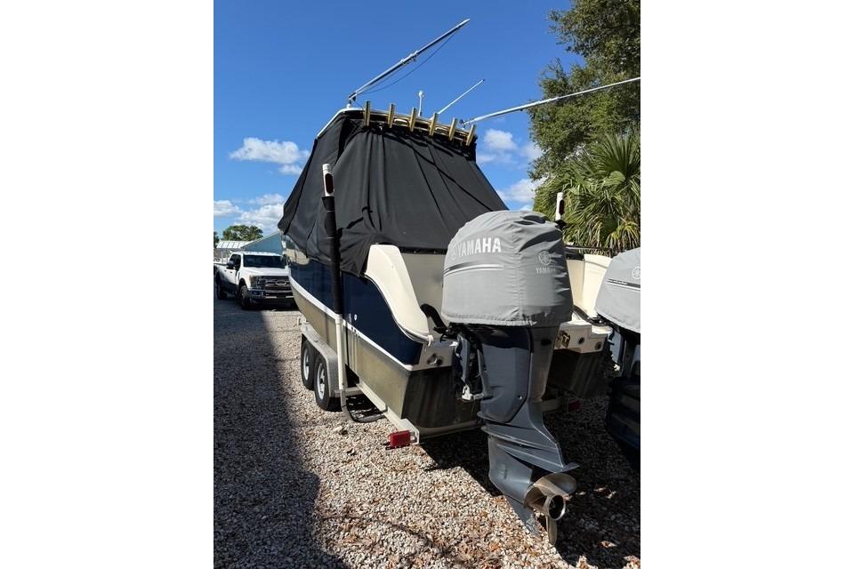 2003 World Cat 270 EC boat with Yamaha engines, covered and parked on gravel.
