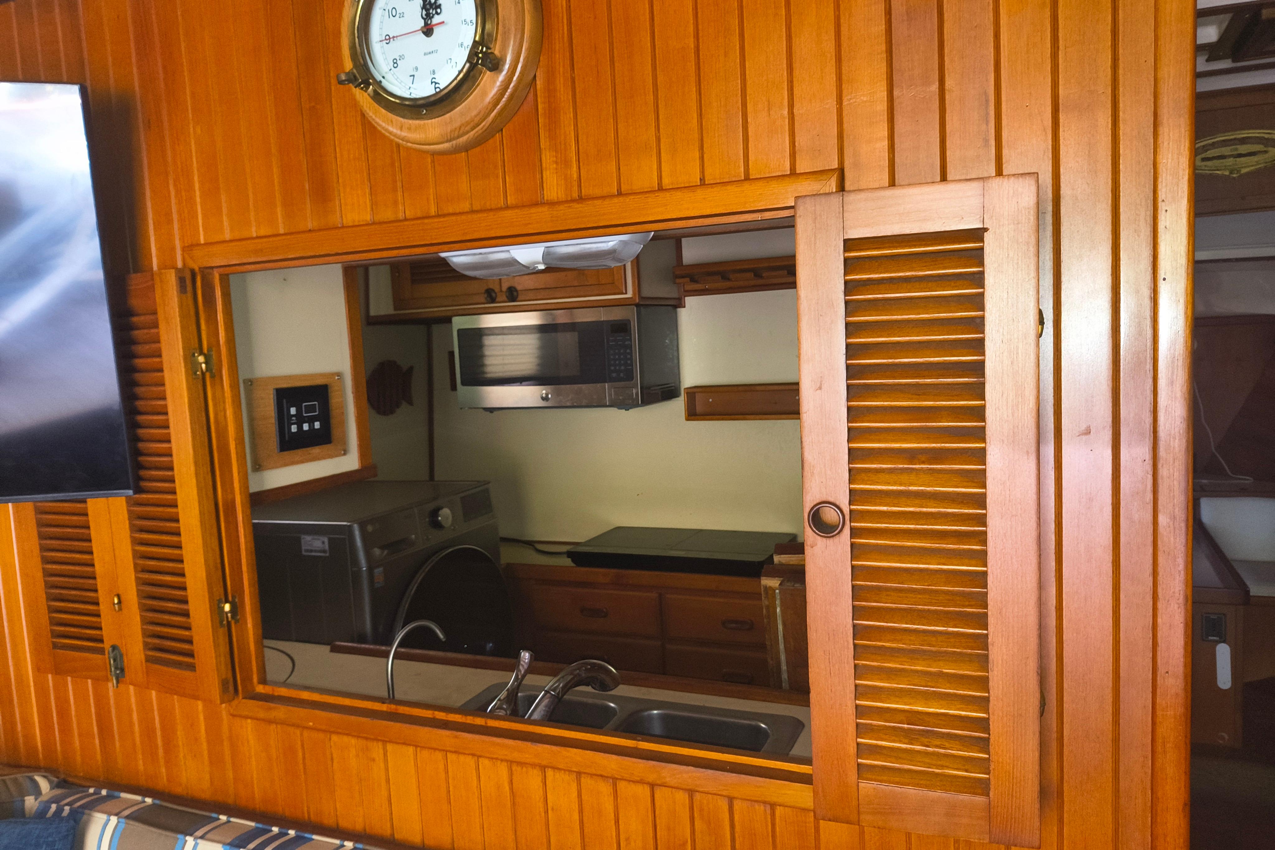 1984 Kadey-Krogen Manatee interior with wooden paneling, kitchen view, and nautical clock.