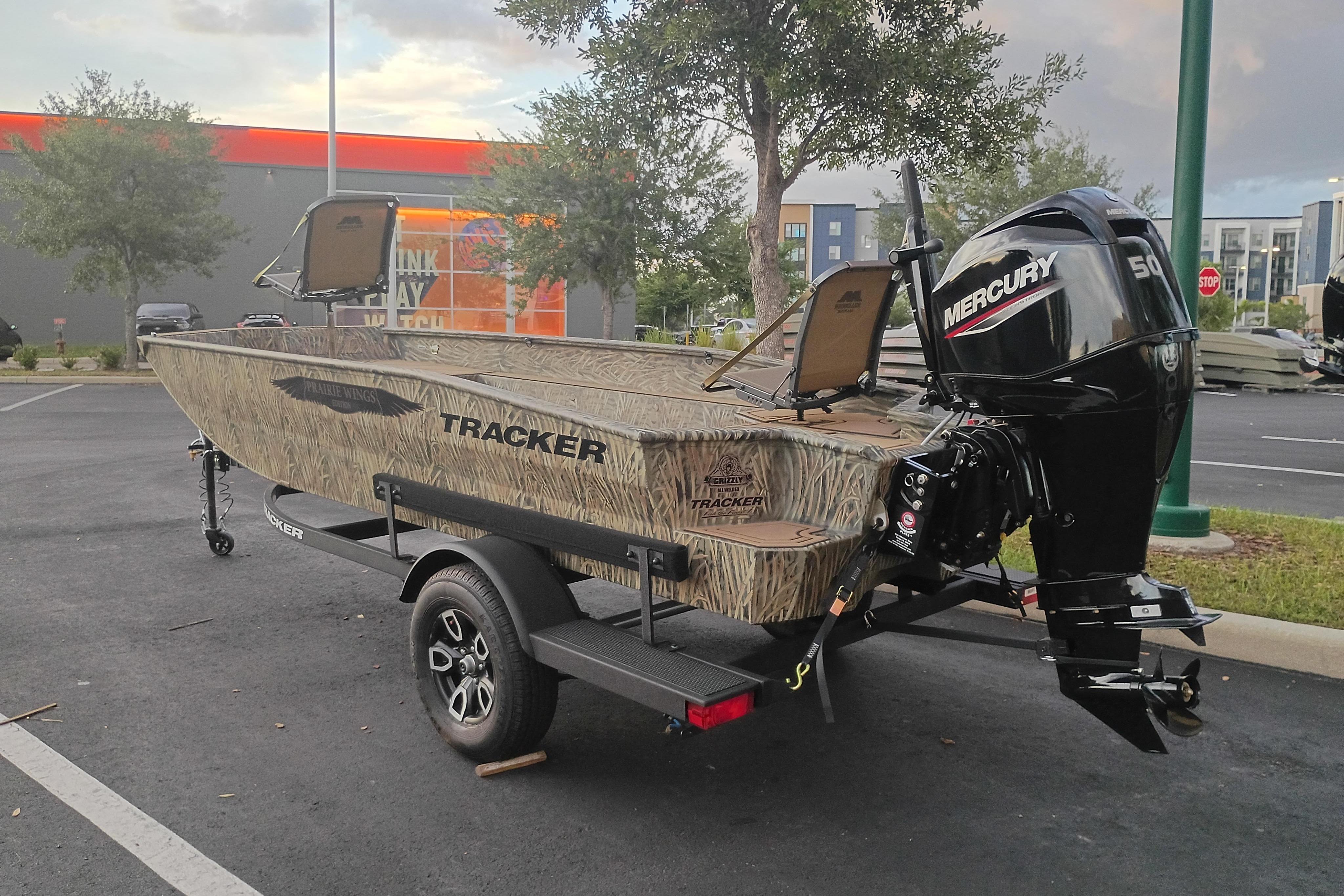 2026 Tracker Grizzly 1650 T Prairie Wings Edition boat with Mercury engine in parking lot.