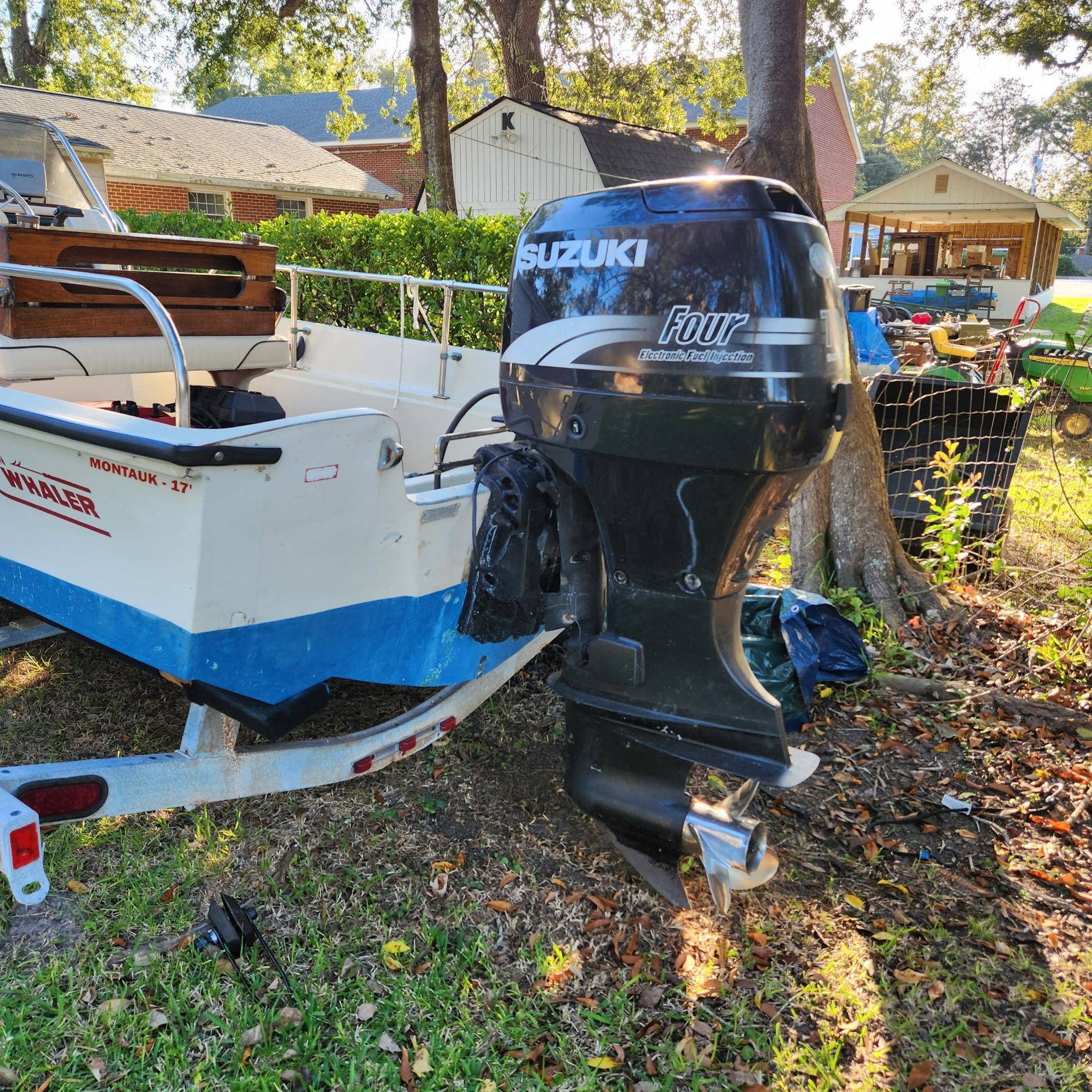 A 1976 Boston Whaler MONTAUK with a Suzuki outboard motor, parked on a trailer outdoors.