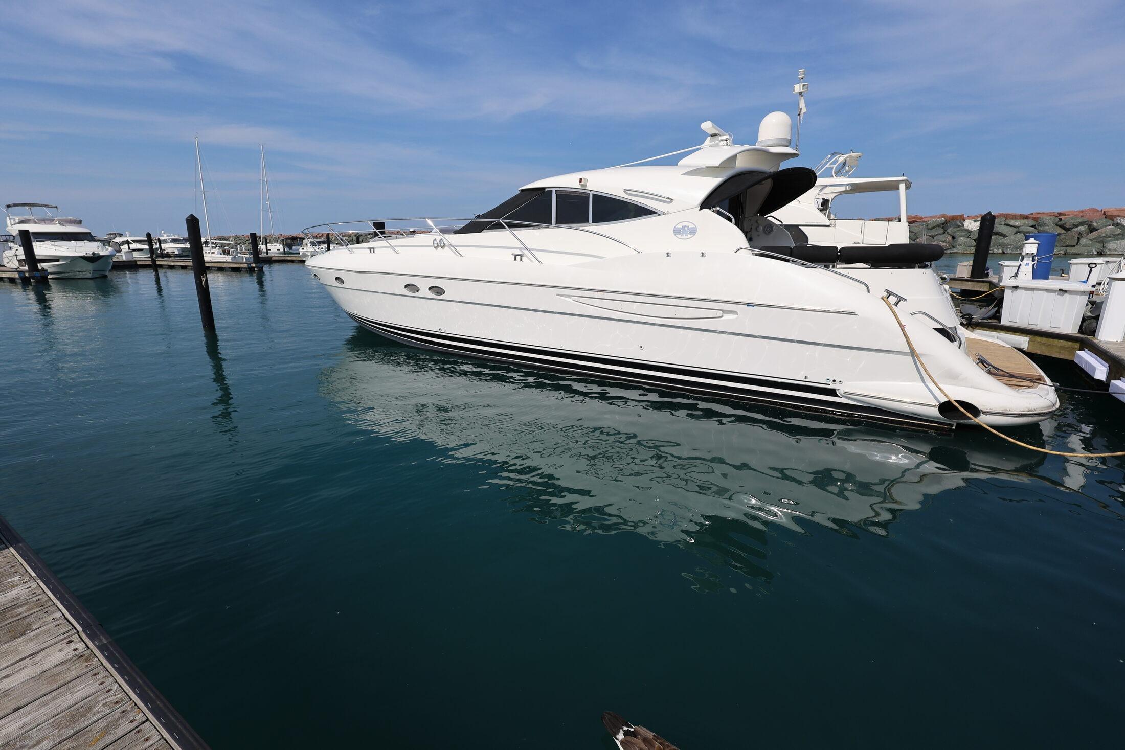 1999 Neptunus 54 Express yacht docked in a marina under a clear blue sky.