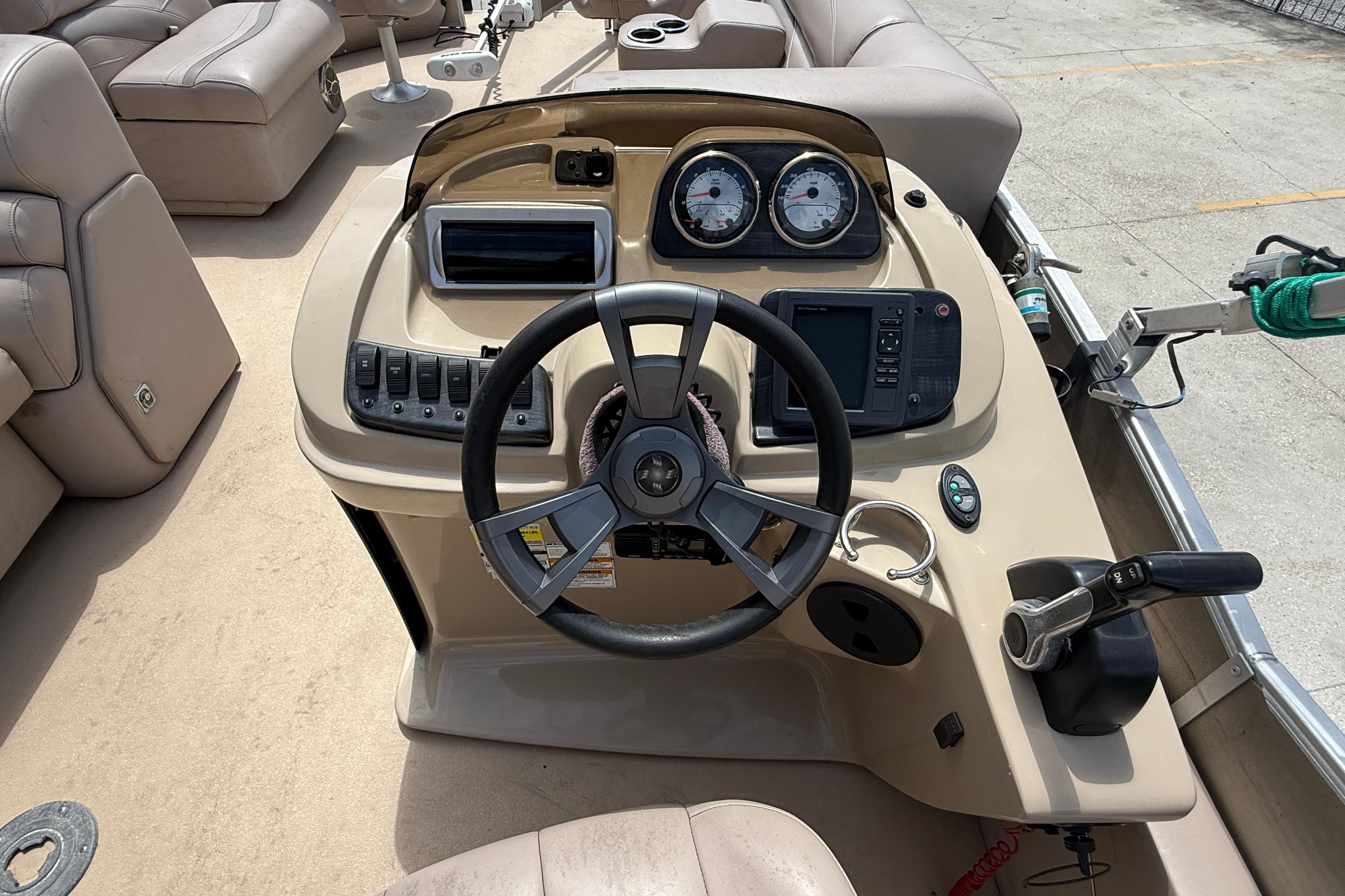Steering console of a 2014 Godfrey Sweetwater 2486 C pontoon boat with gauges and controls.
