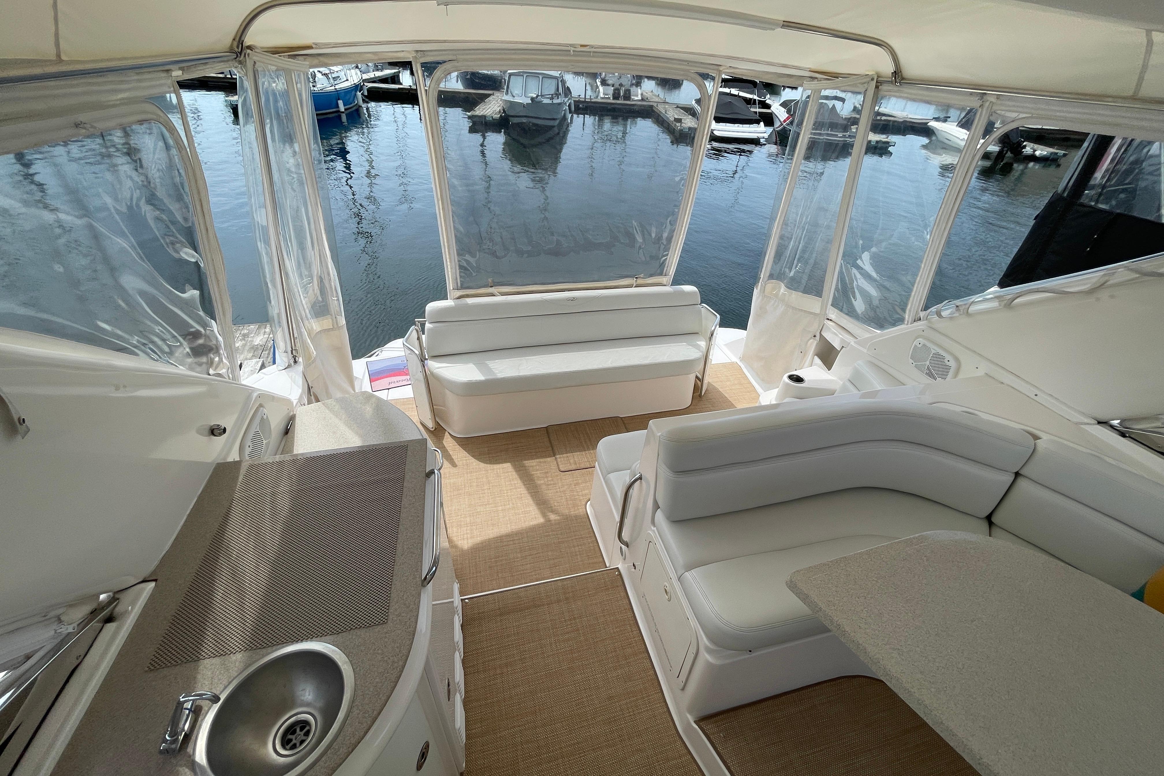 2004 Regal Commodore 4260 yacht interior with seating, table, and sink, overlooking marina.