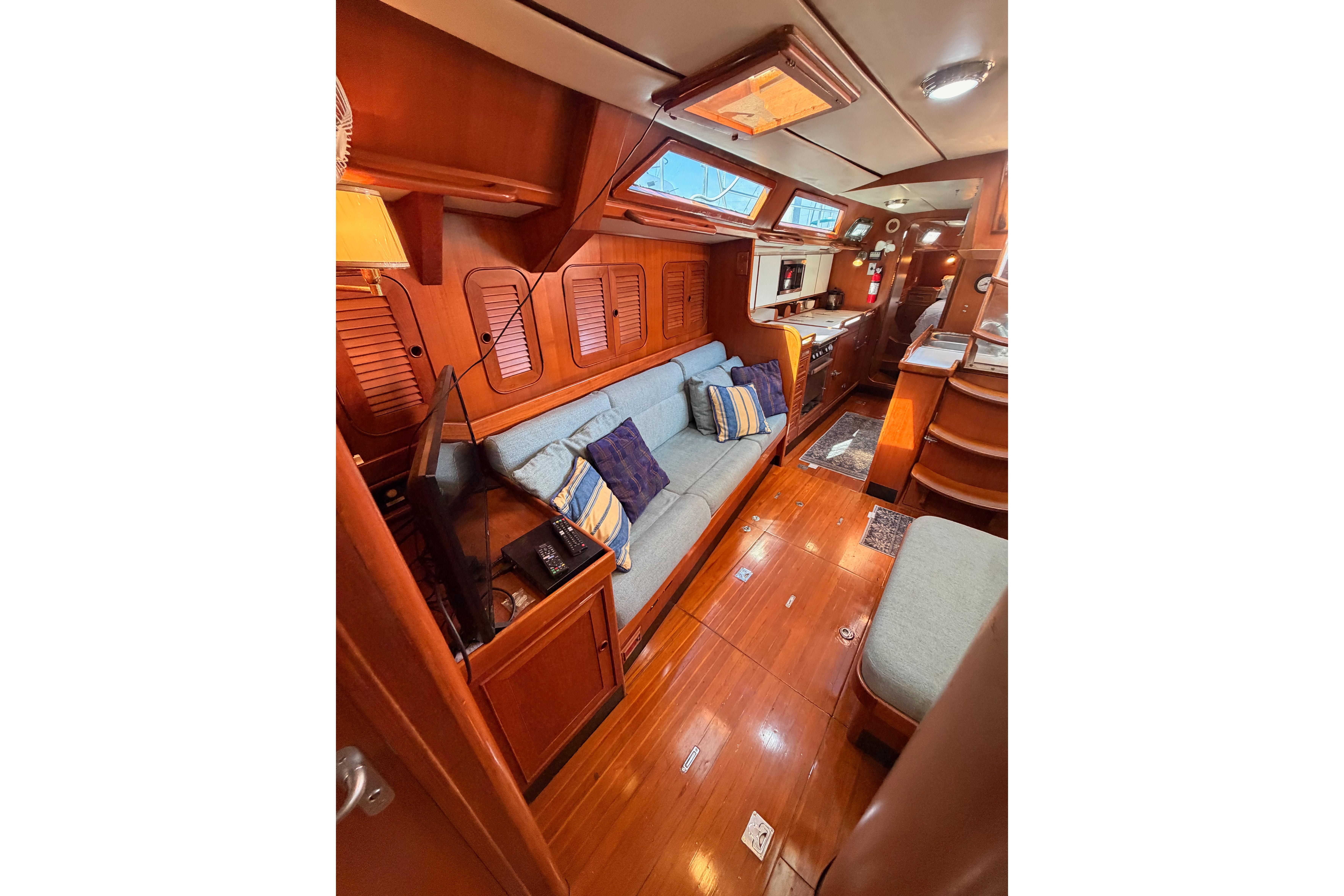 Luxurious 1991 Hylas 51 yacht interior with wooden finishes and cozy seating area.