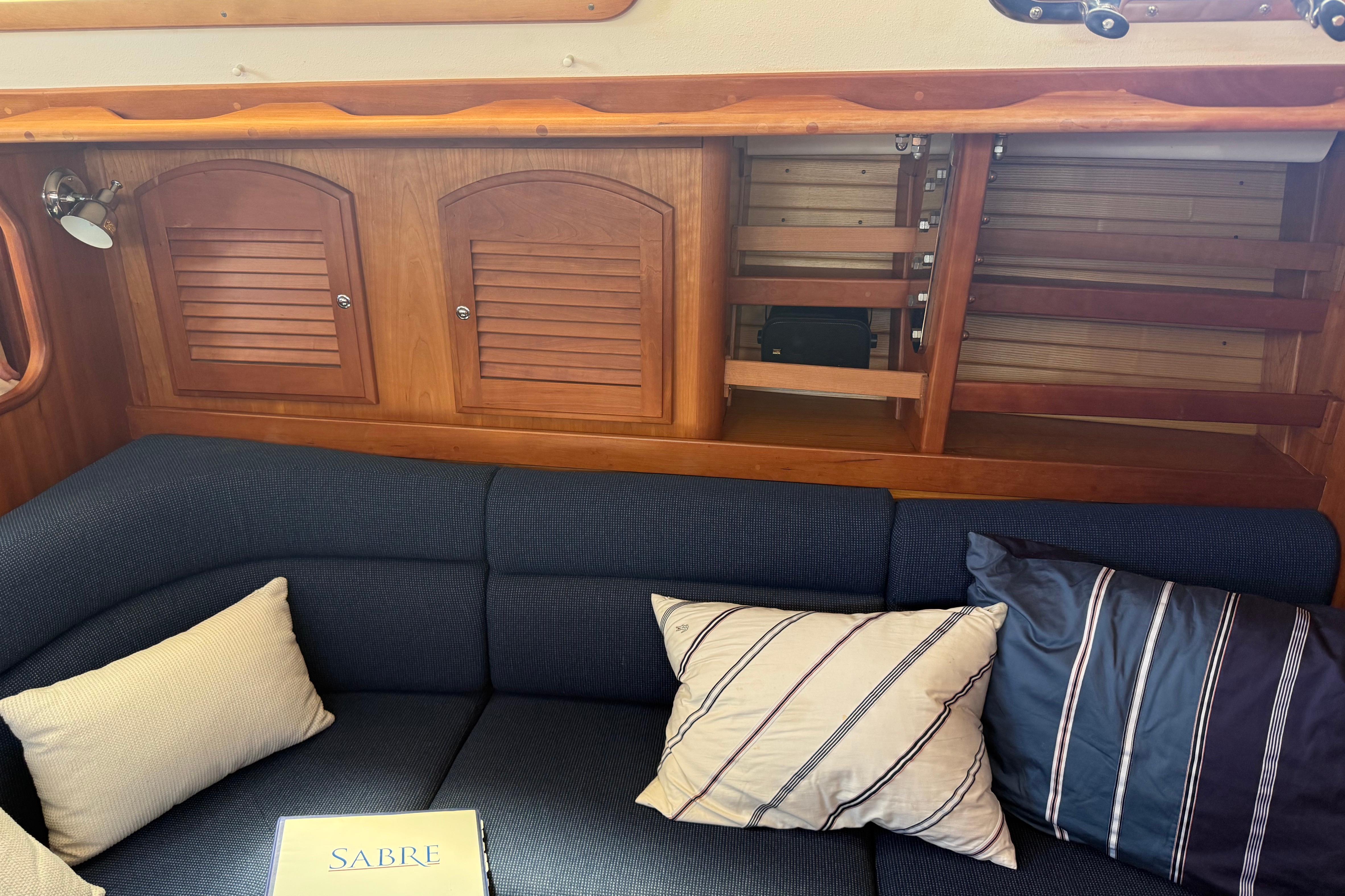 Cozy interior of 2004 Sabre 386 yacht with blue cushions and wooden cabinetry.
