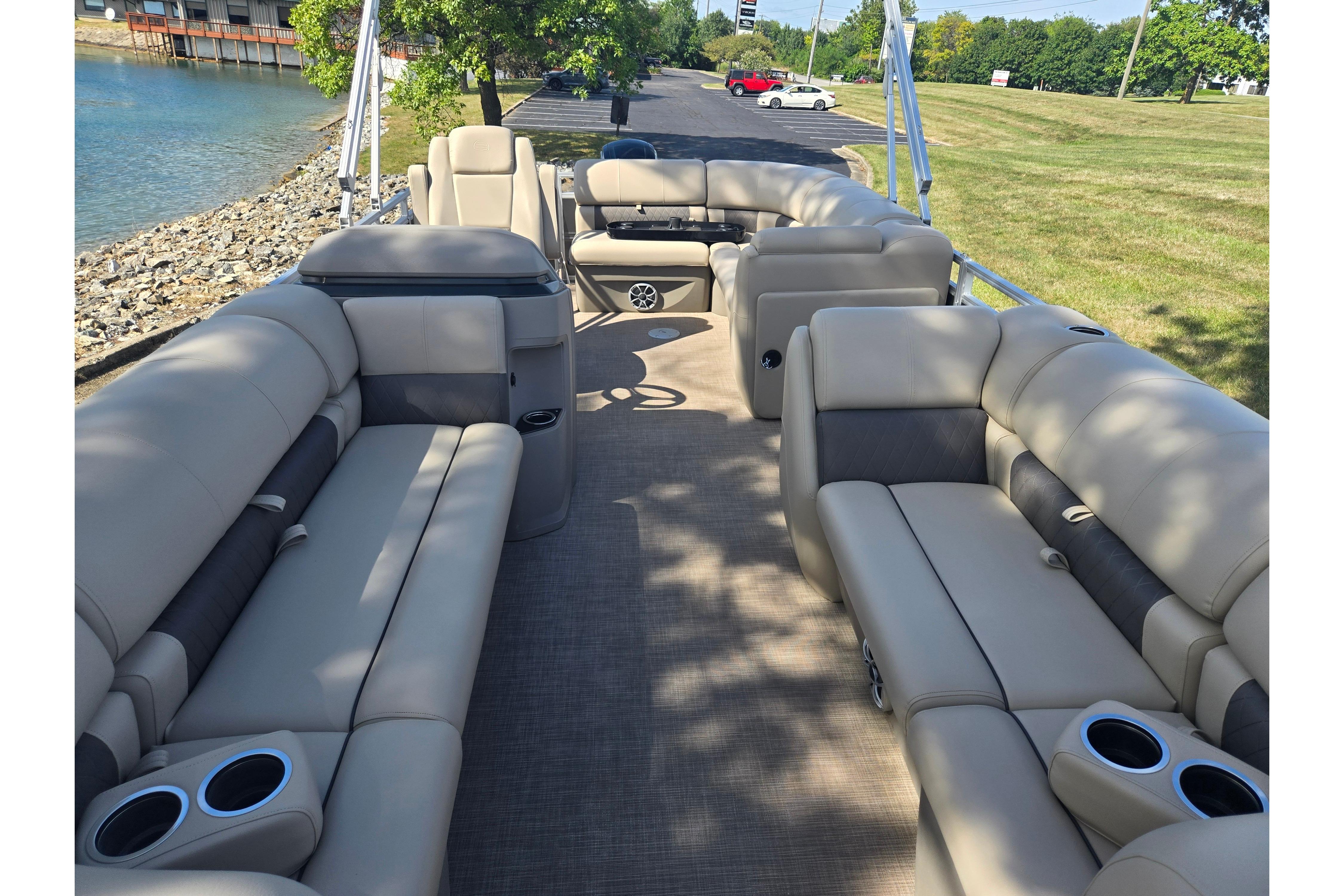 2024 Sun Tracker Party Barge 20 DLX with spacious seating and cup holders by the water.