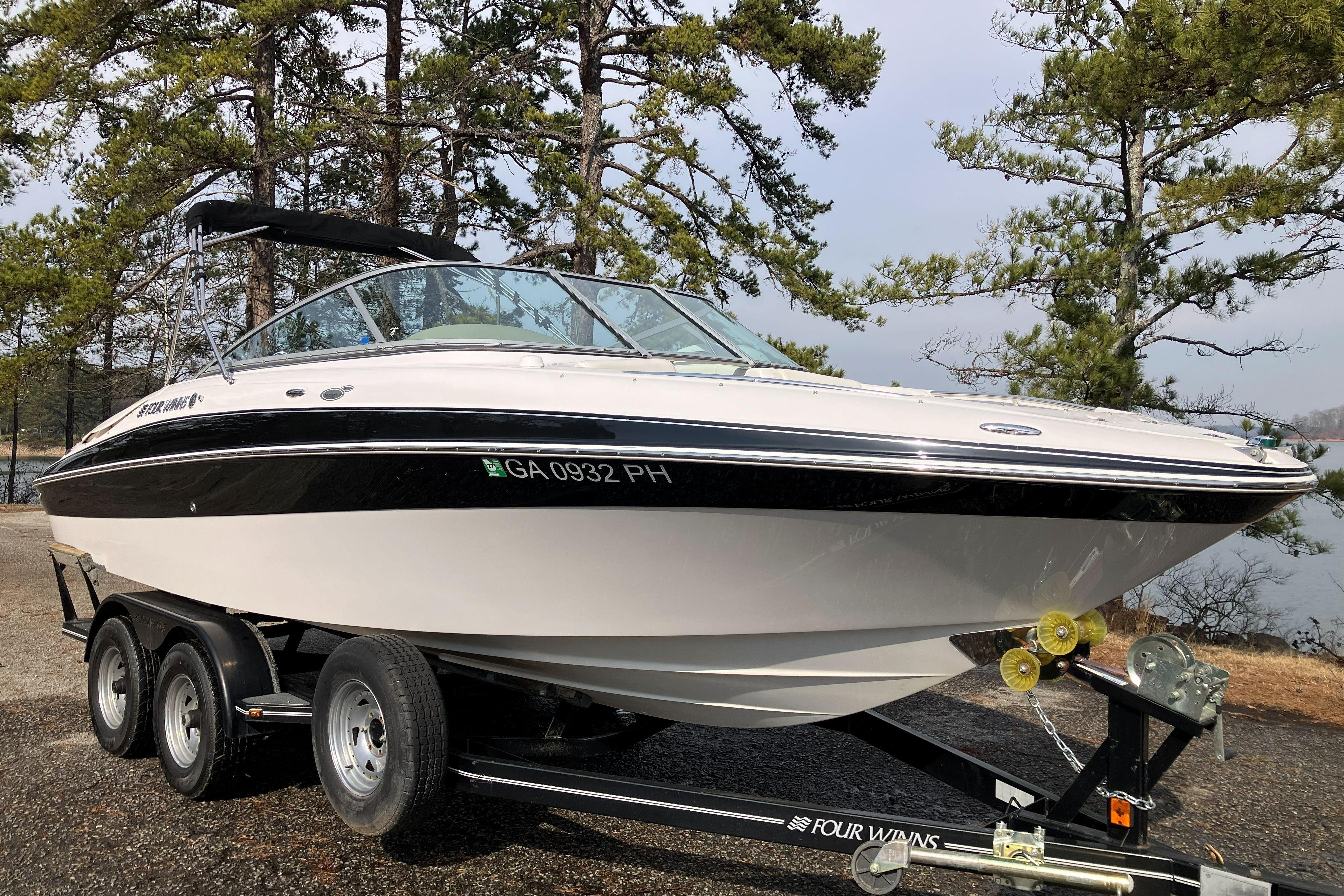 2006 Four Winns 240 Horizon boat on trailer, surrounded by trees.