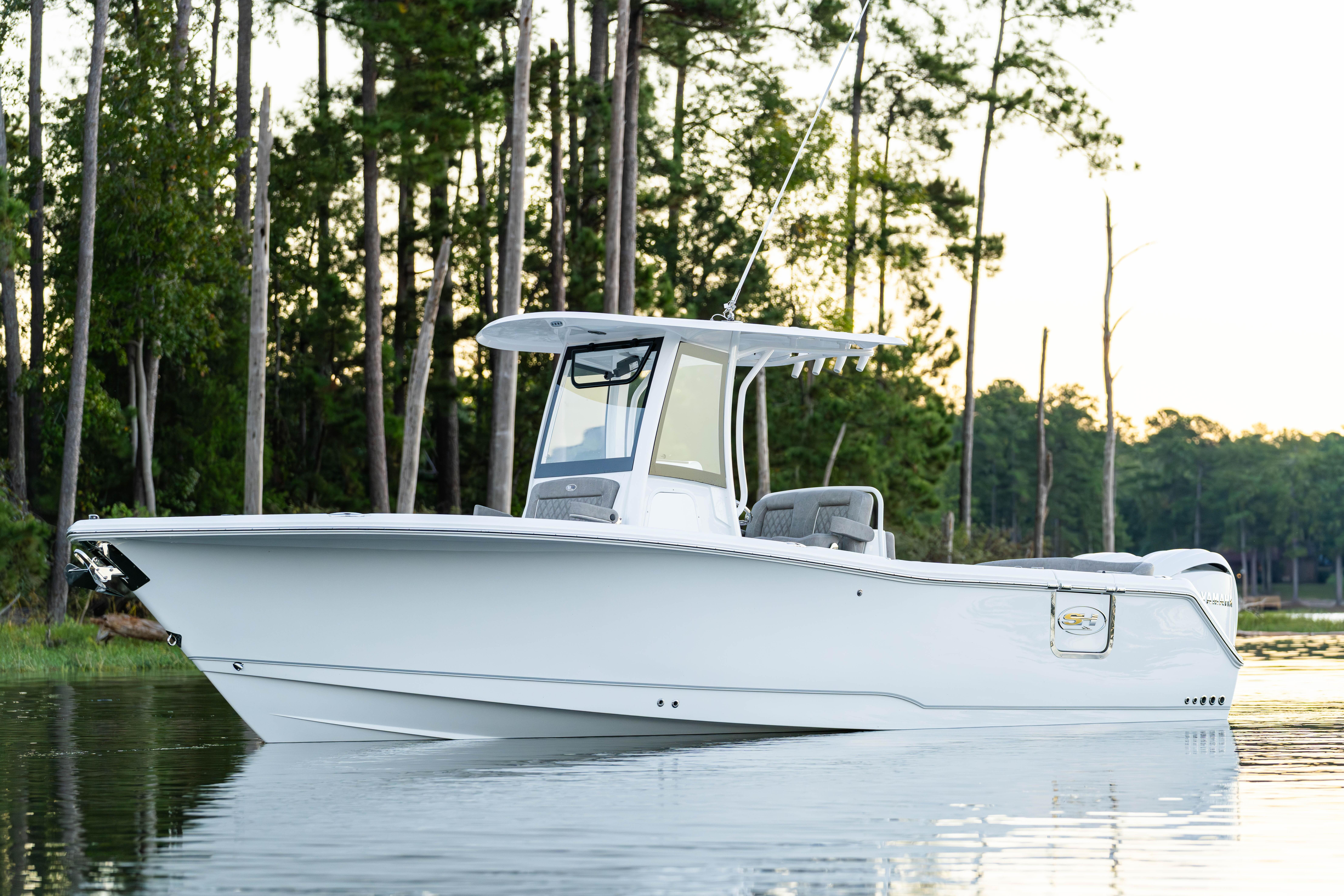 2026 Sea Hunt Ultra 275 Coffin Box boat on calm water, surrounded by trees.