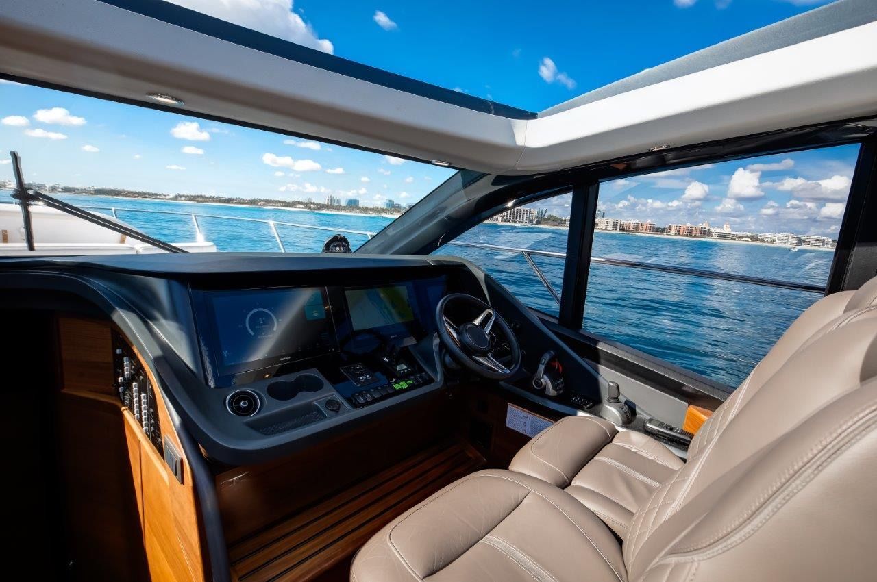 The image shows the cockpit of a 2025 Princess V55 yacht with a modern helm and sea view.