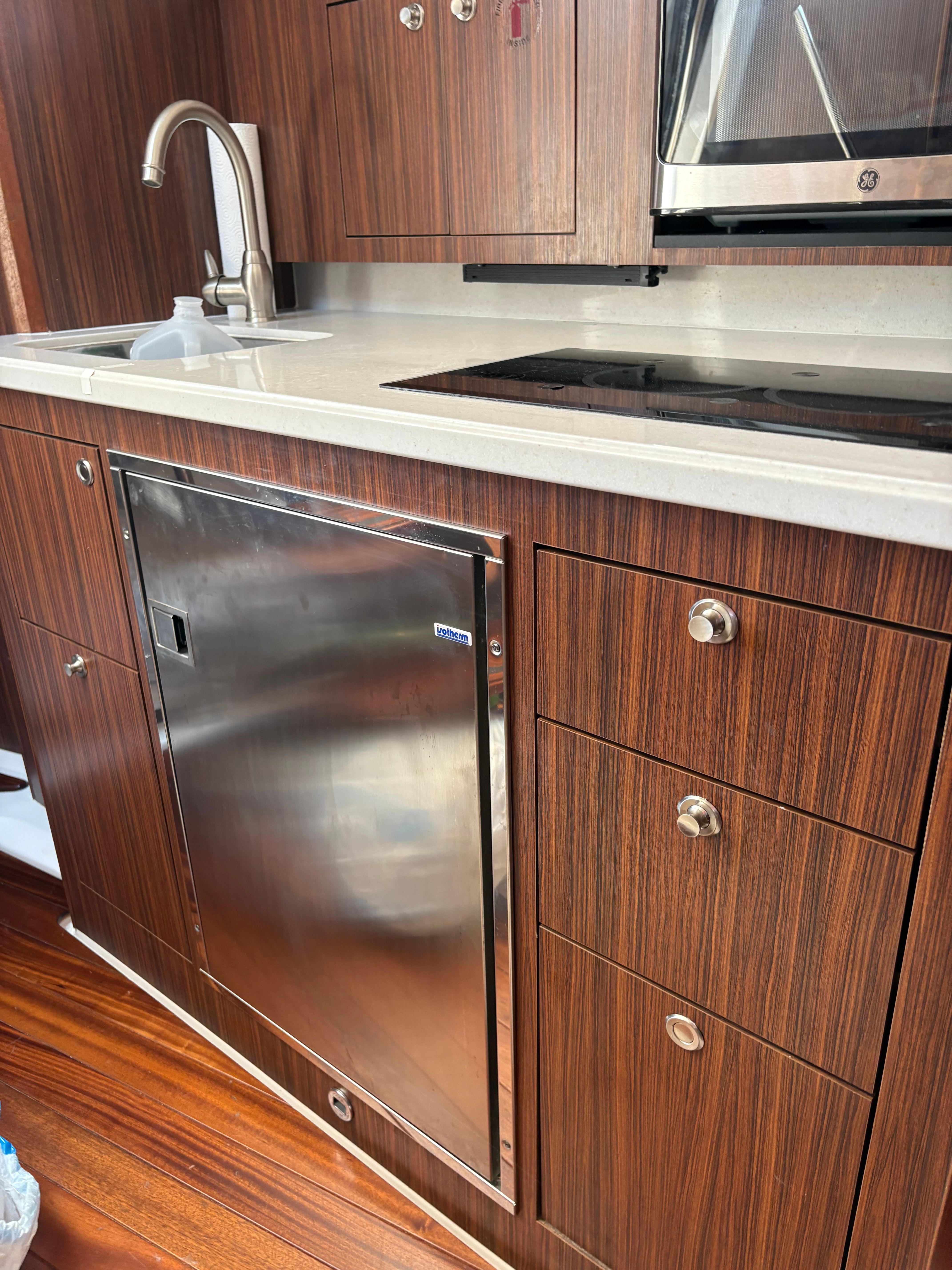 2017 Pursuit OS 355 Offshore kitchen with wood cabinetry, stainless steel appliances, and modern fixtures.