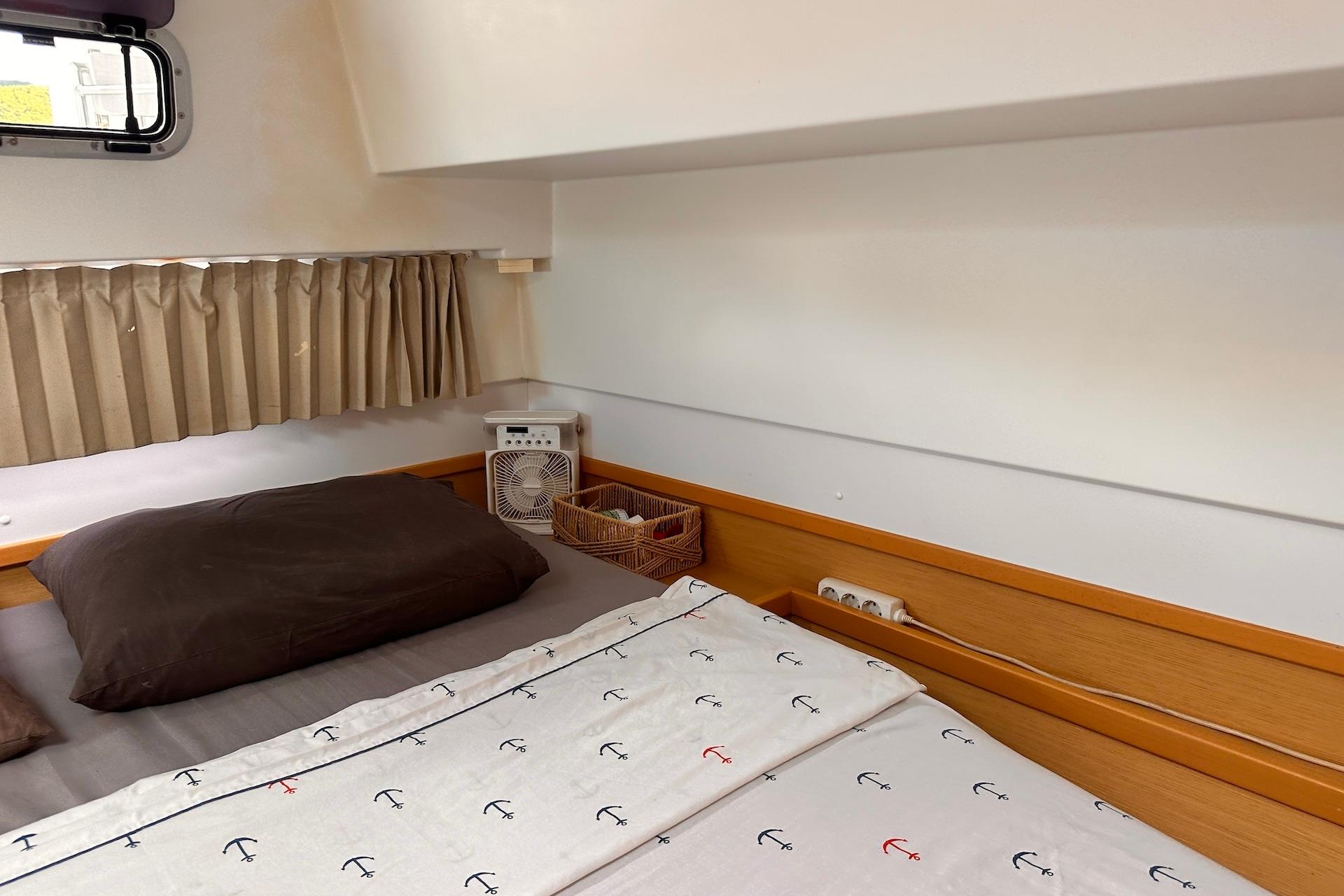 Cozy cabin interior of 2016 Lagoon 42 catamaran with nautical-themed bedding.