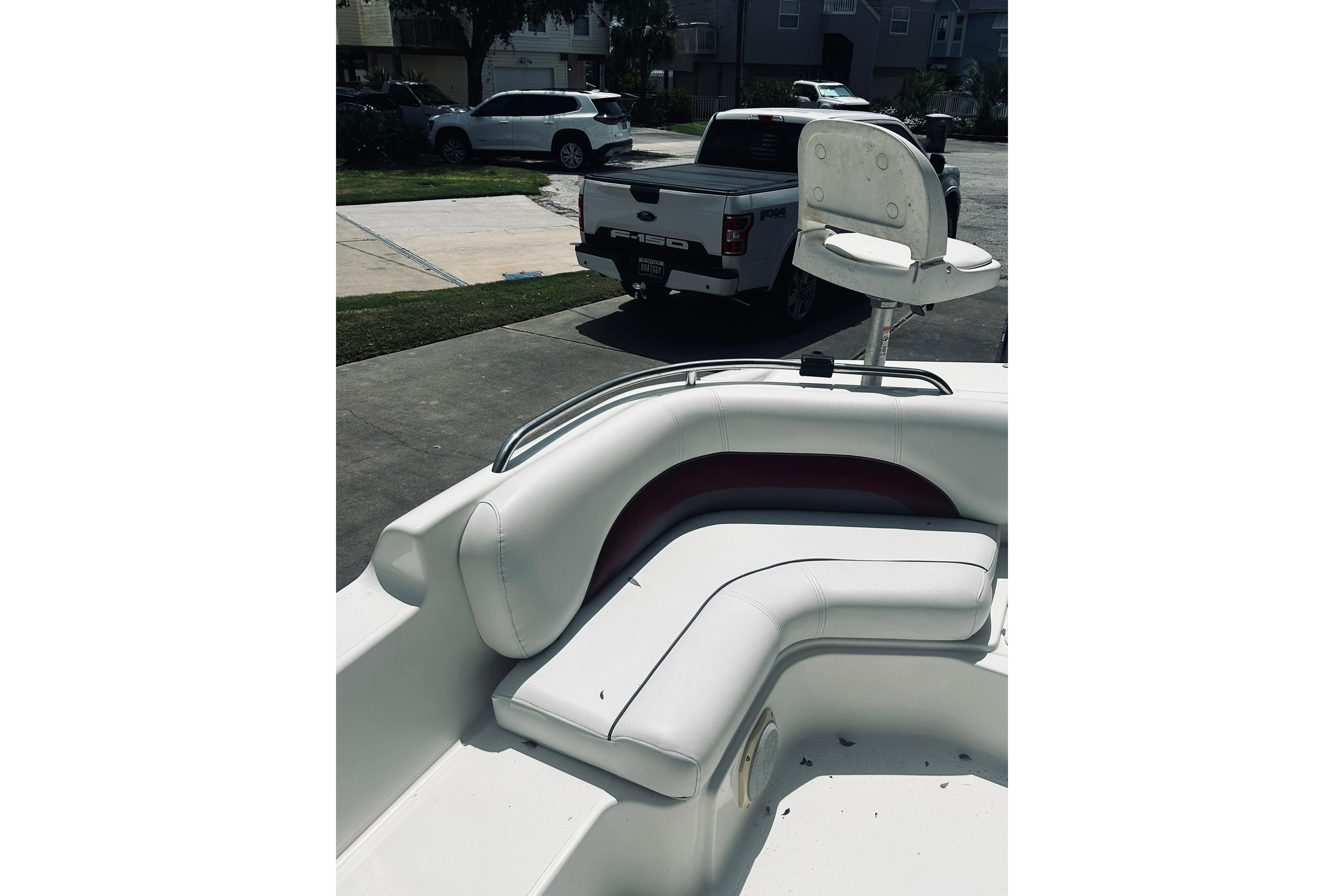 2013 Hurricane SunDeck Sport 201 OB boat with white seating and a fishing chair.