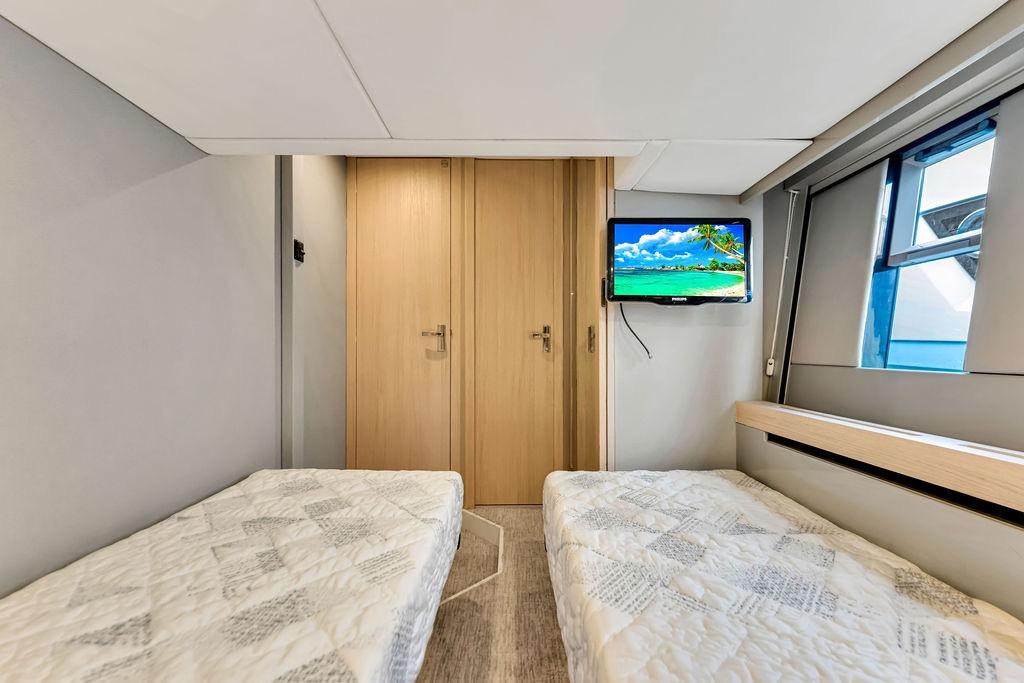 Twin beds in a 2012 Fairline Targa 58 yacht cabin with TV and window view.