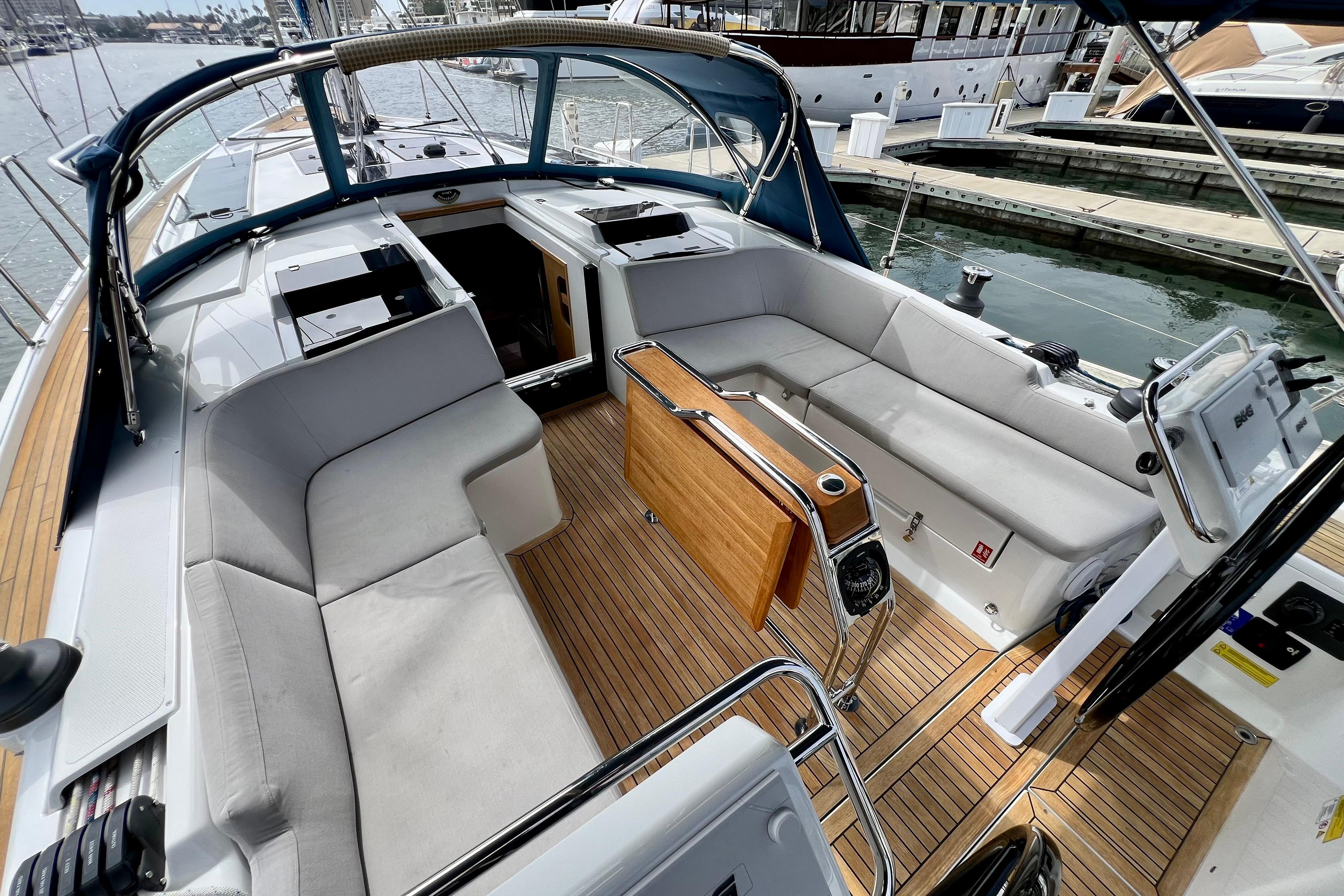 2016 Hanse 455 yacht cockpit with cushioned seating and wooden flooring at marina.