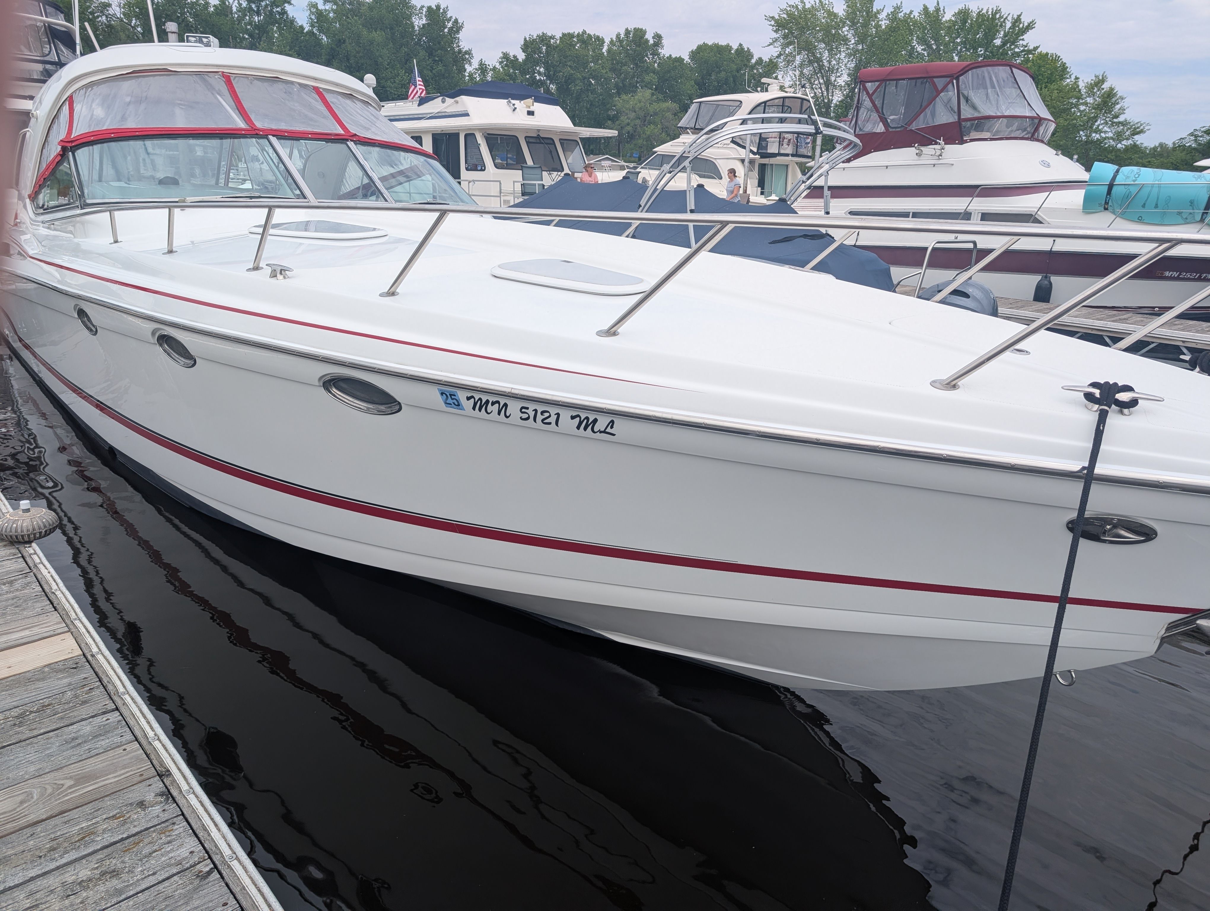 A white motor yacht docked, featuring red accents and a spacious deck.