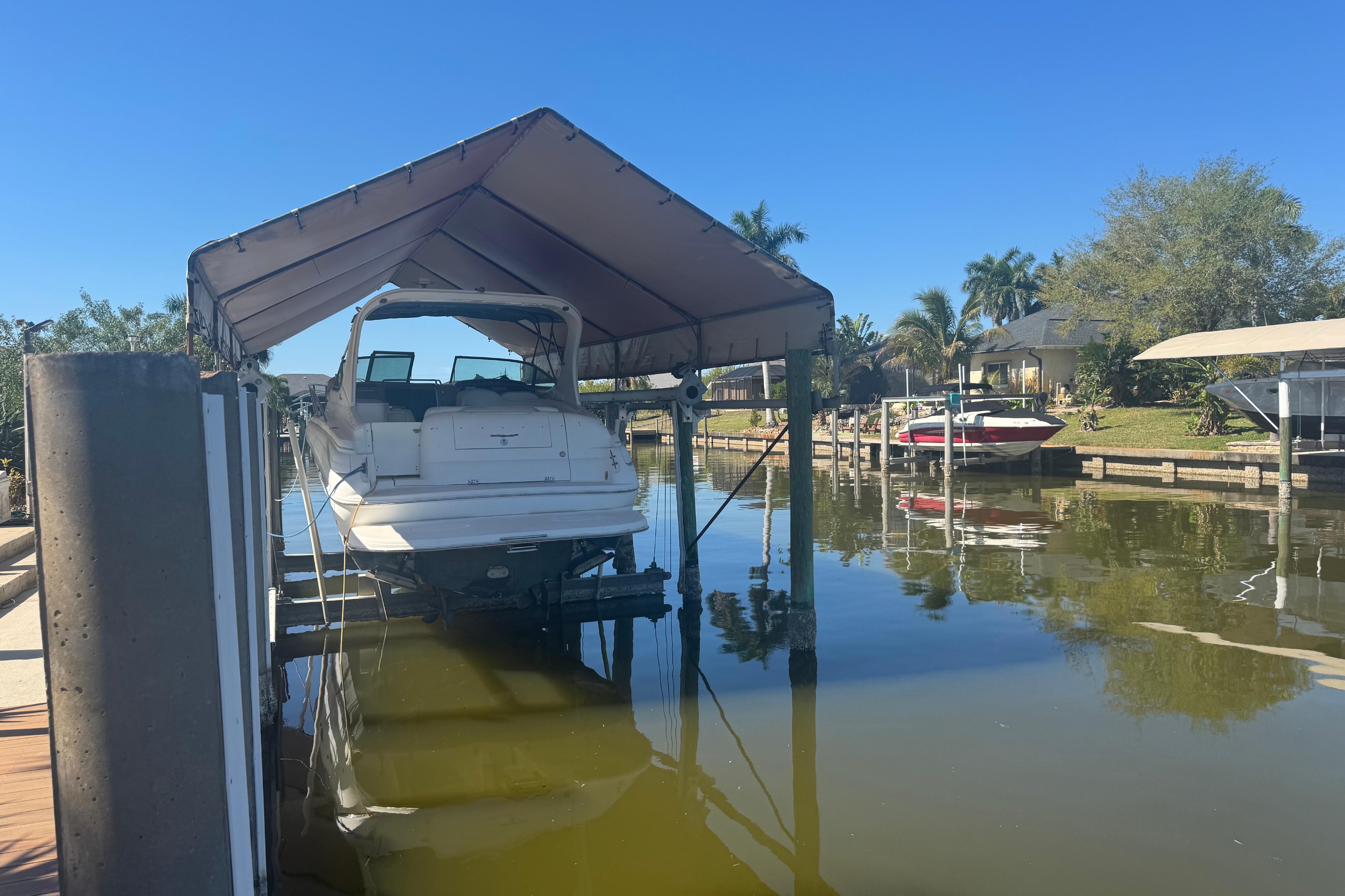 2002 Wellcraft 3300 Martinique boat docked under canopy on a sunny day.
