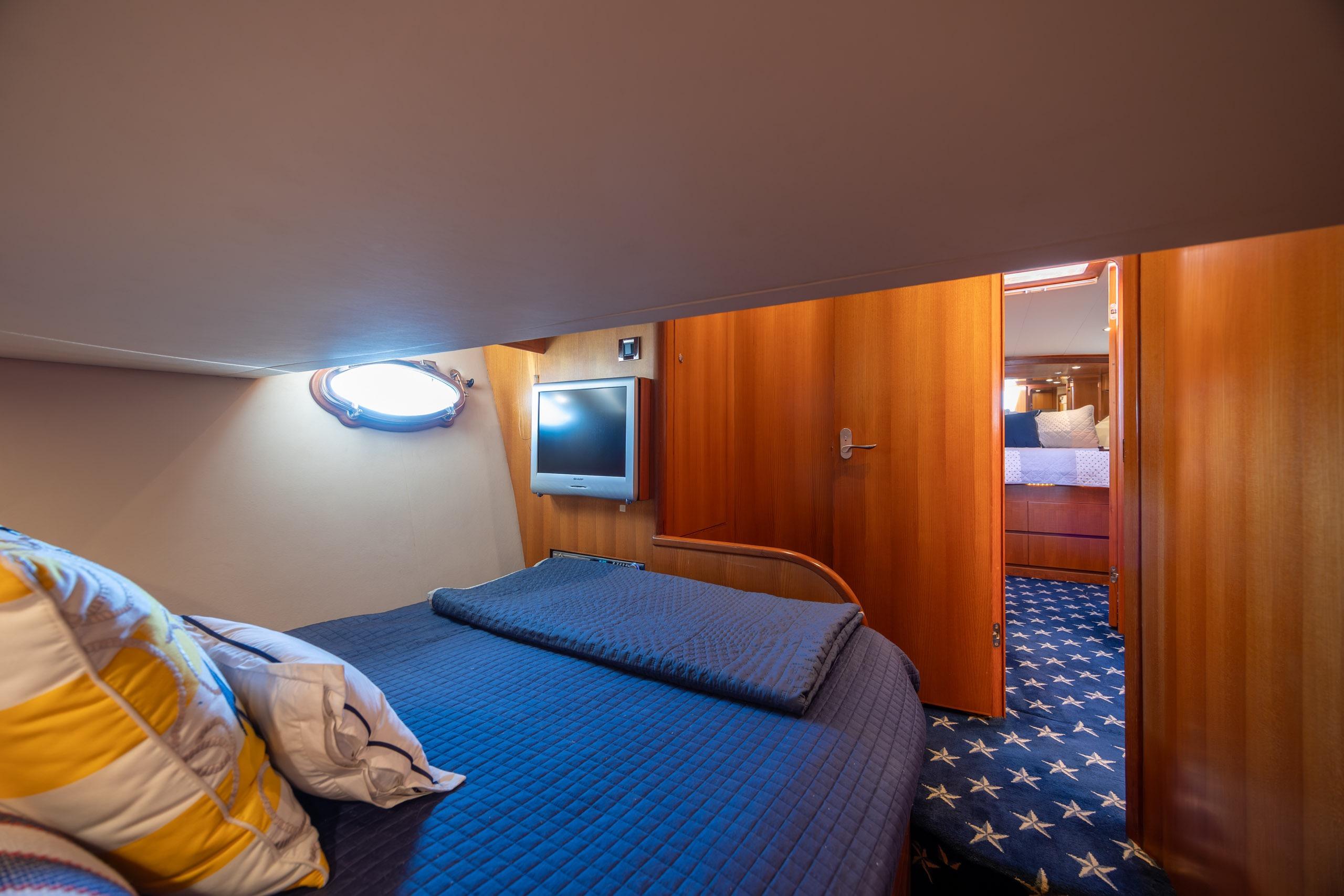 Luxurious cabin interior of 2005 Ocean Alexander 52 Sedan yacht with cozy bedding and wood paneling.
