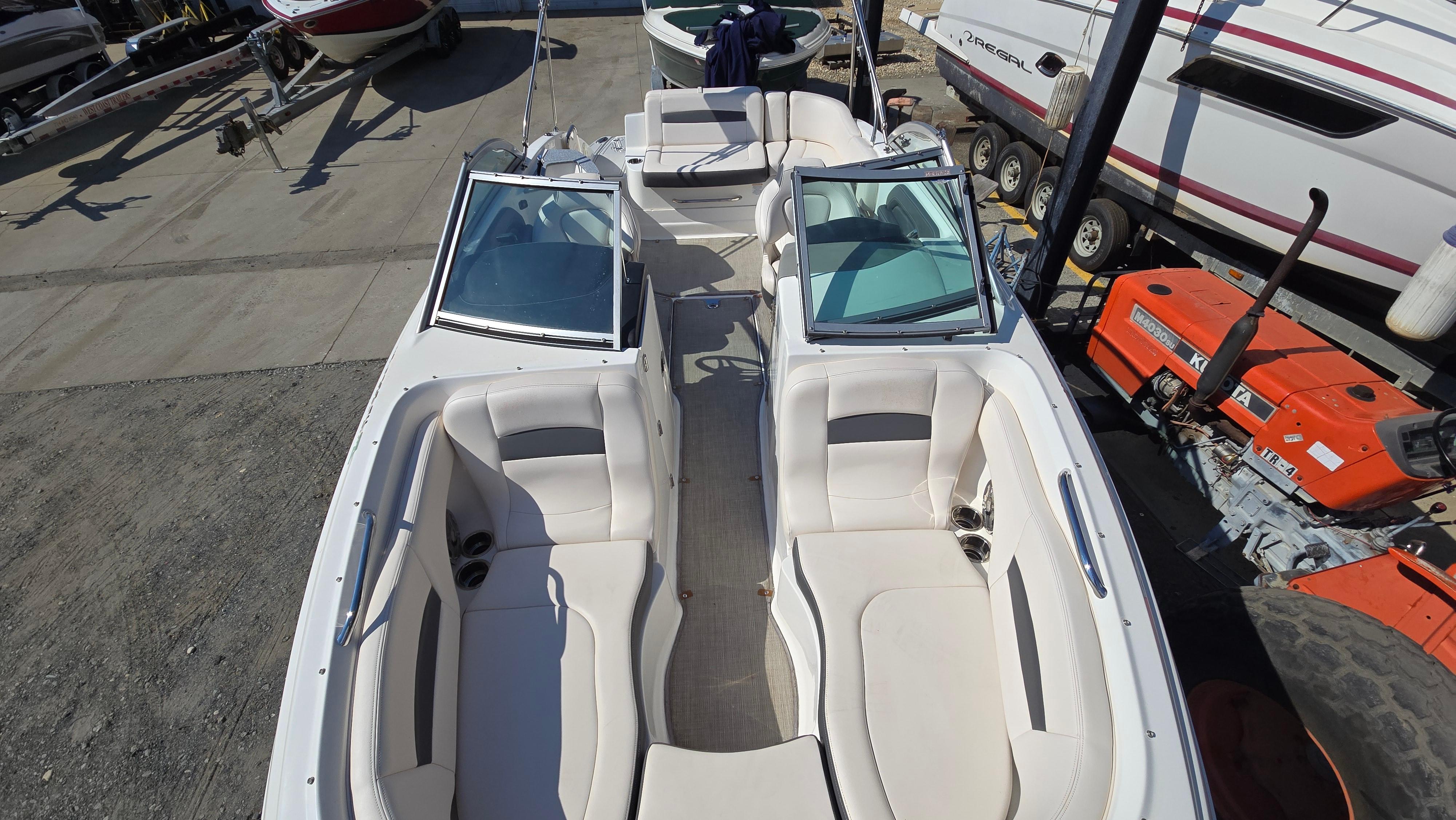 2018 Chaparral 224 Sunesta boat interior with white seating, docked near other boats.