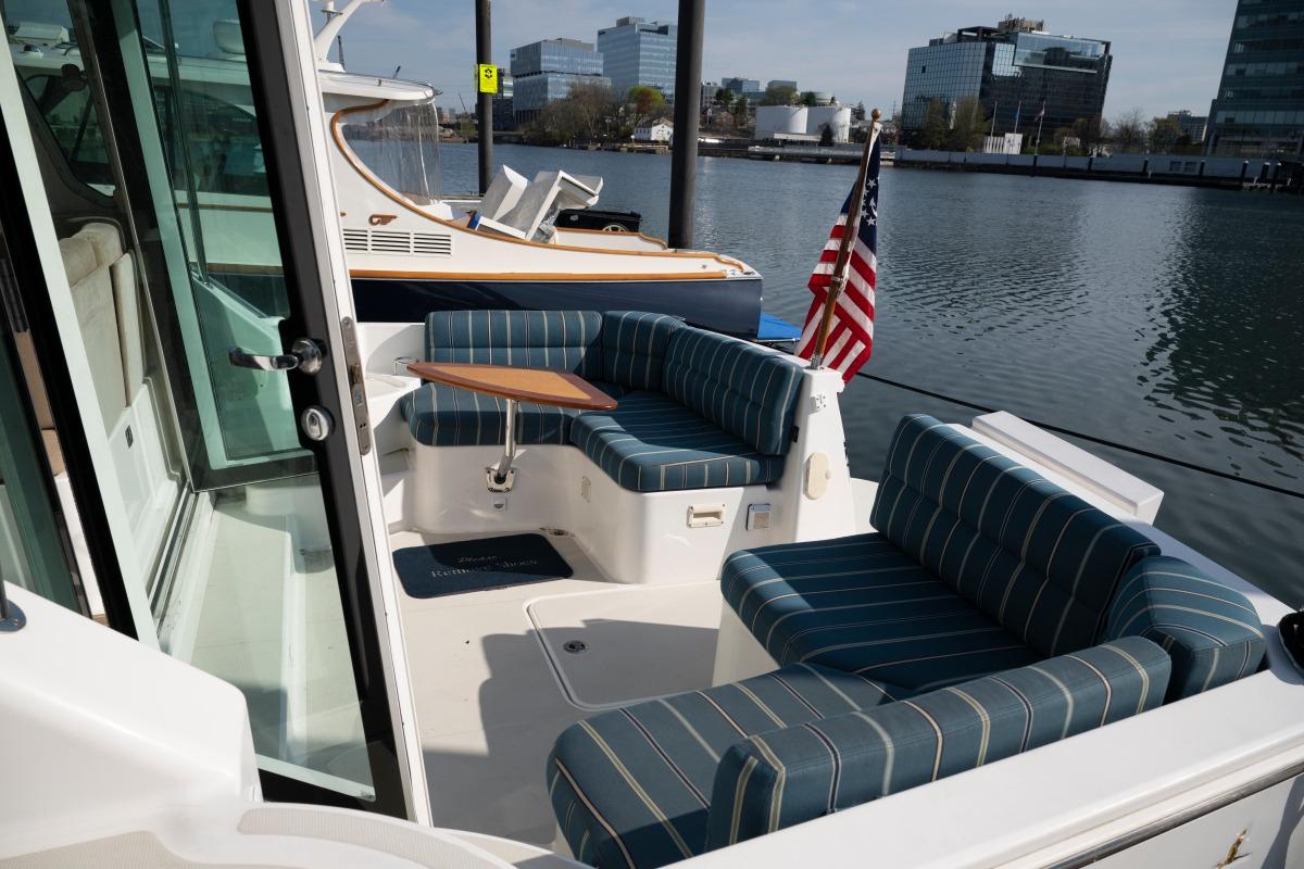 2014 Back Cove 37 yacht with striped seating, docked by waterfront buildings.