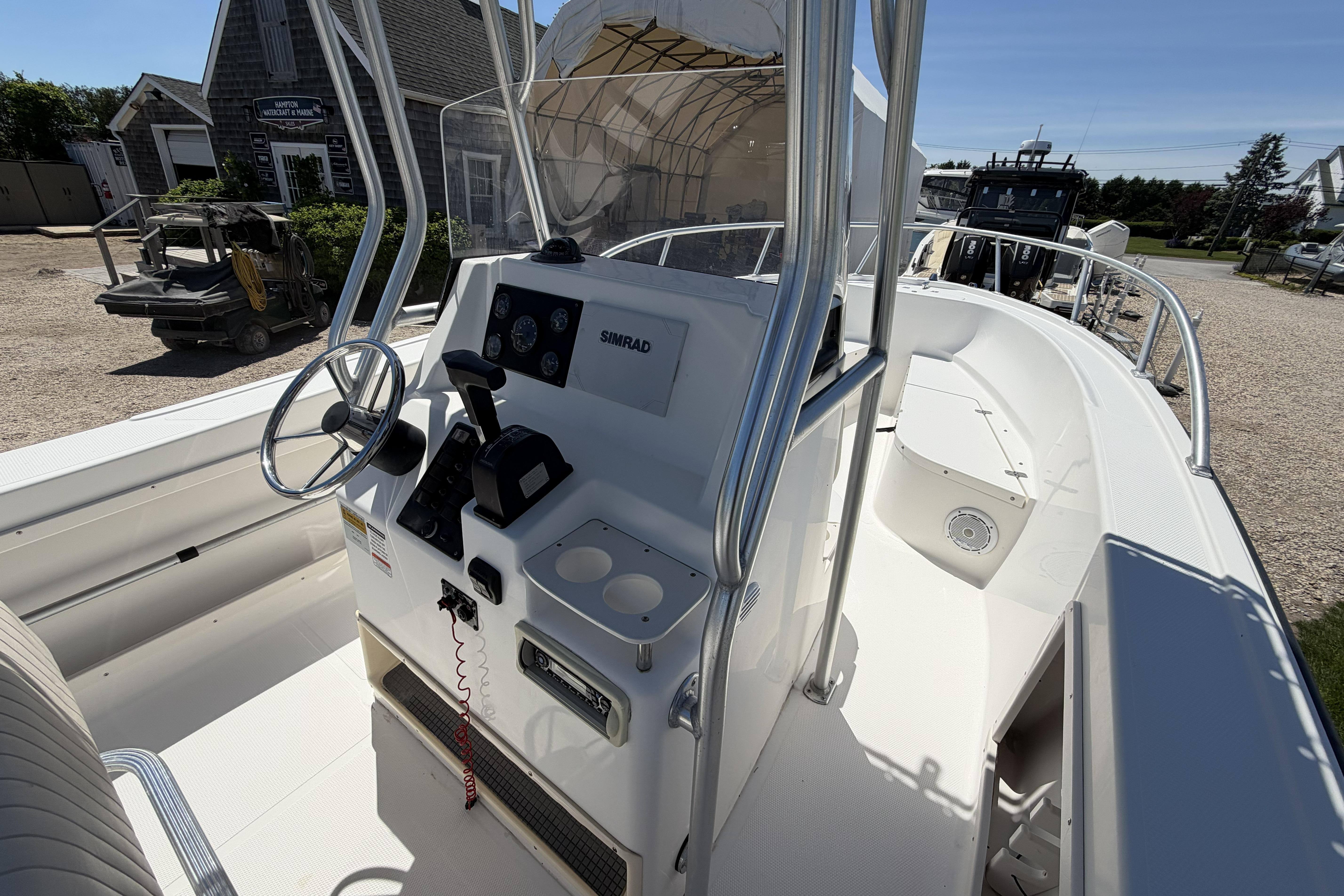2006 Mako 212 Center Console boat with steering wheel and control panel, docked outdoors.