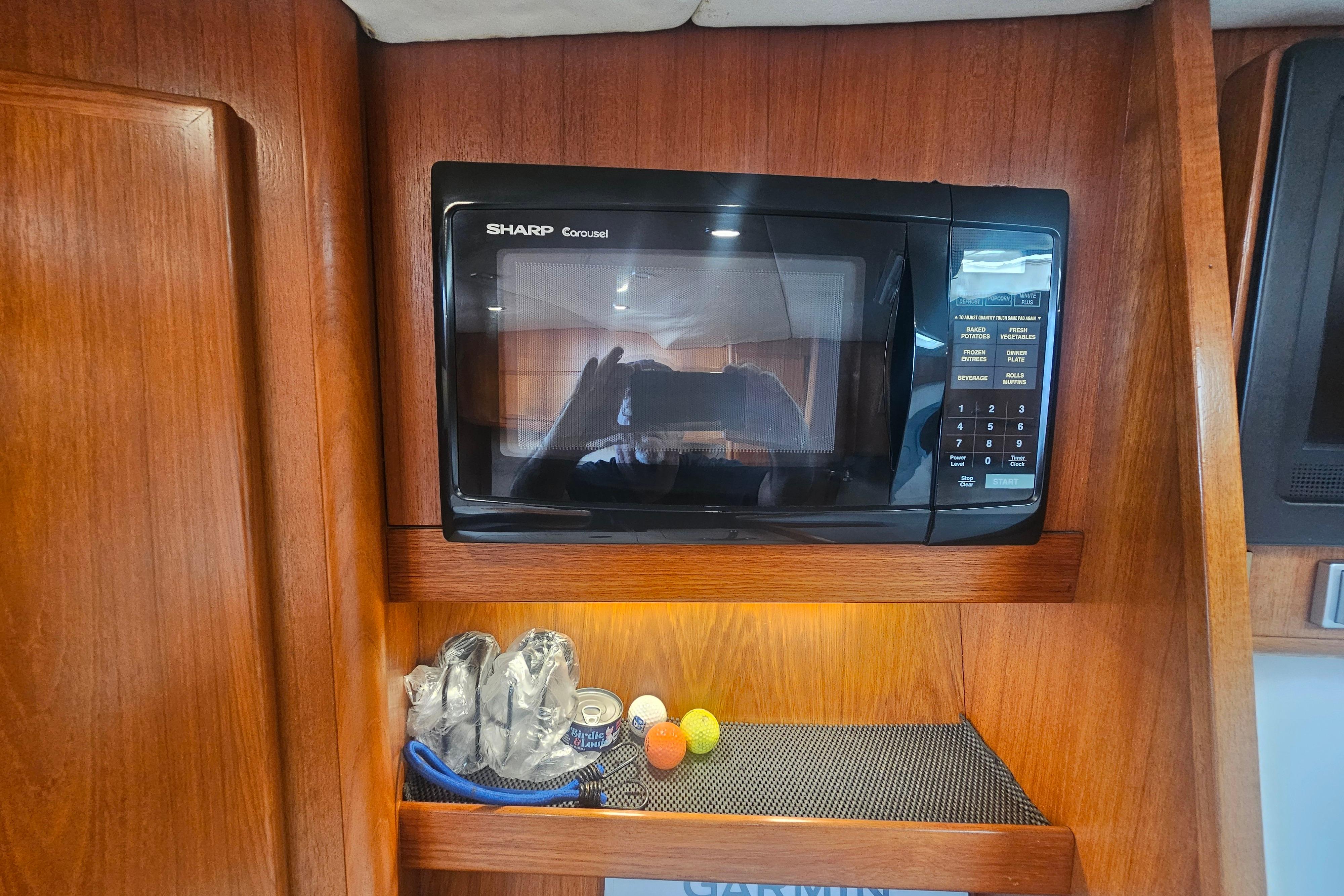 Sharp Carousel microwave in 2003 Topaz 32 Express boat interior with wooden cabinetry.