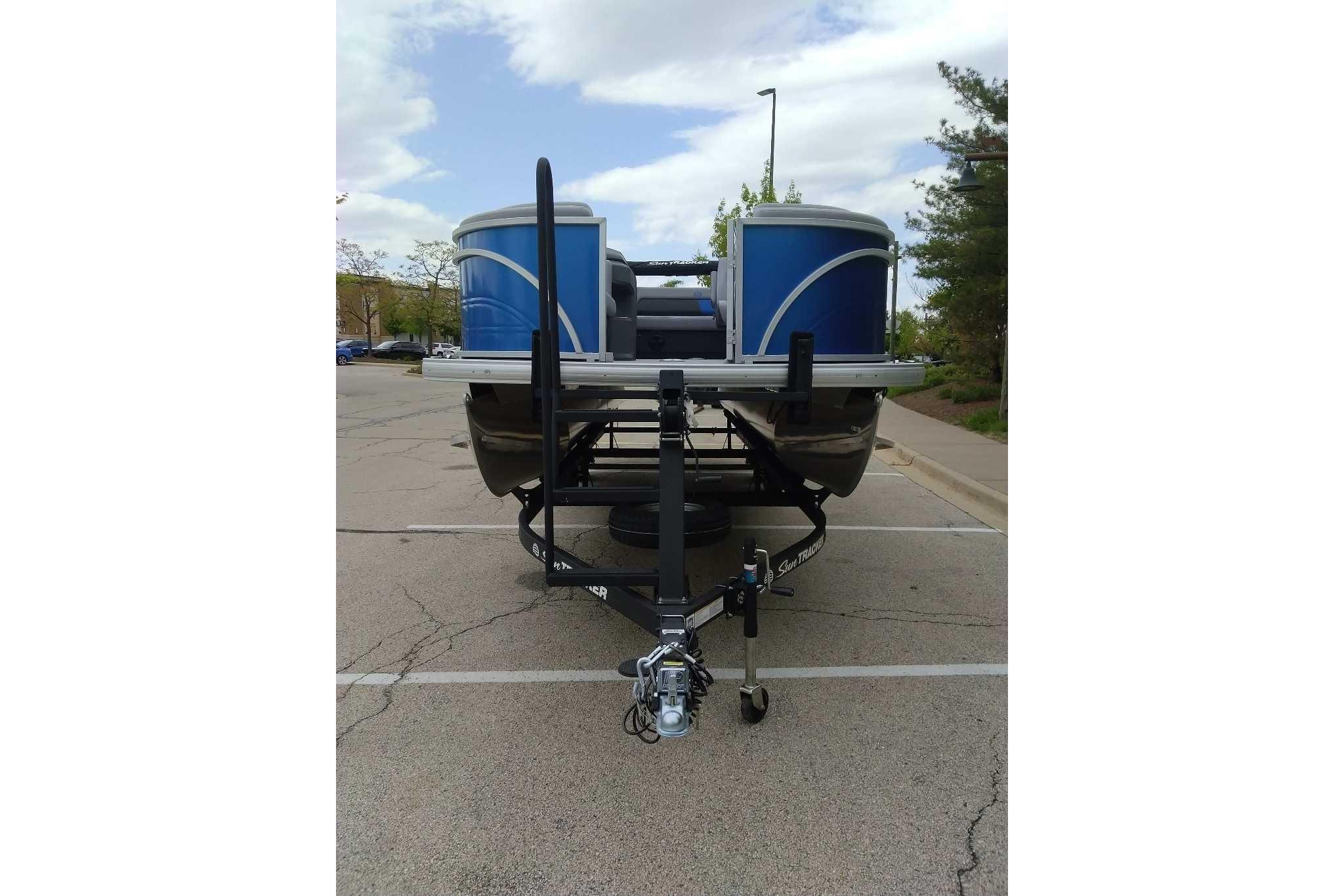 2026 Sun Tracker Party Barge 22 RF DLX pontoon boat on trailer in parking lot.