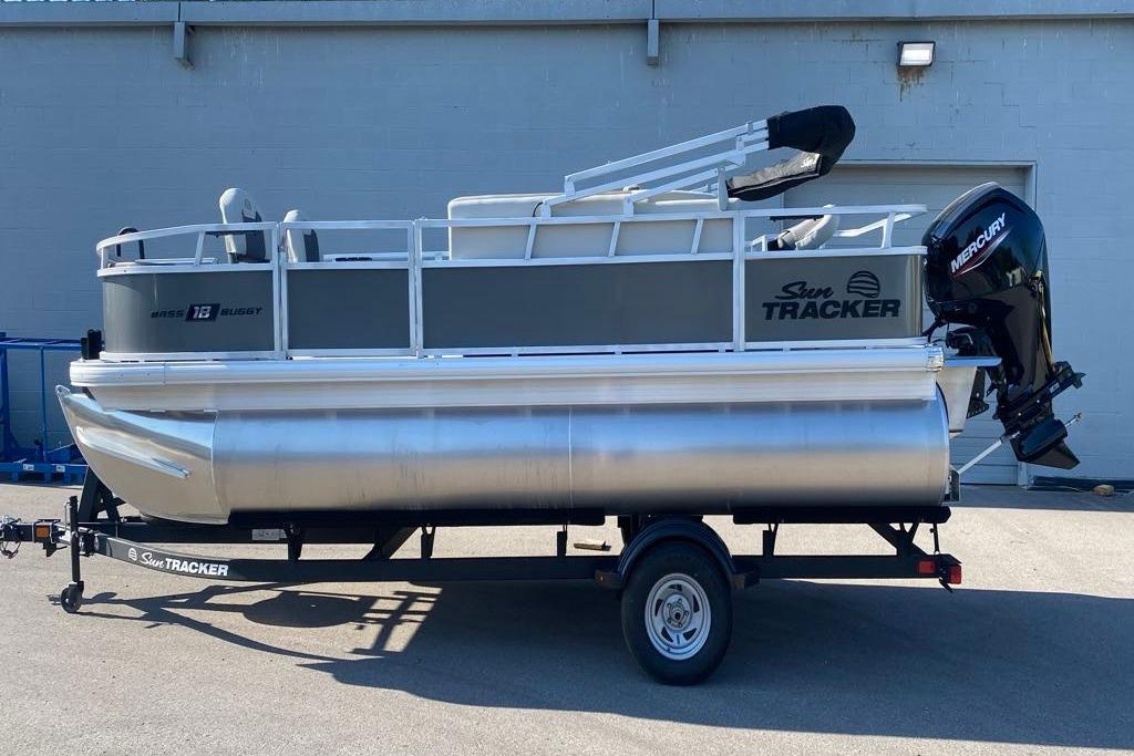 2026 Sun Tracker Bass Buggy 18 DLX pontoon boat on trailer, parked outdoors.