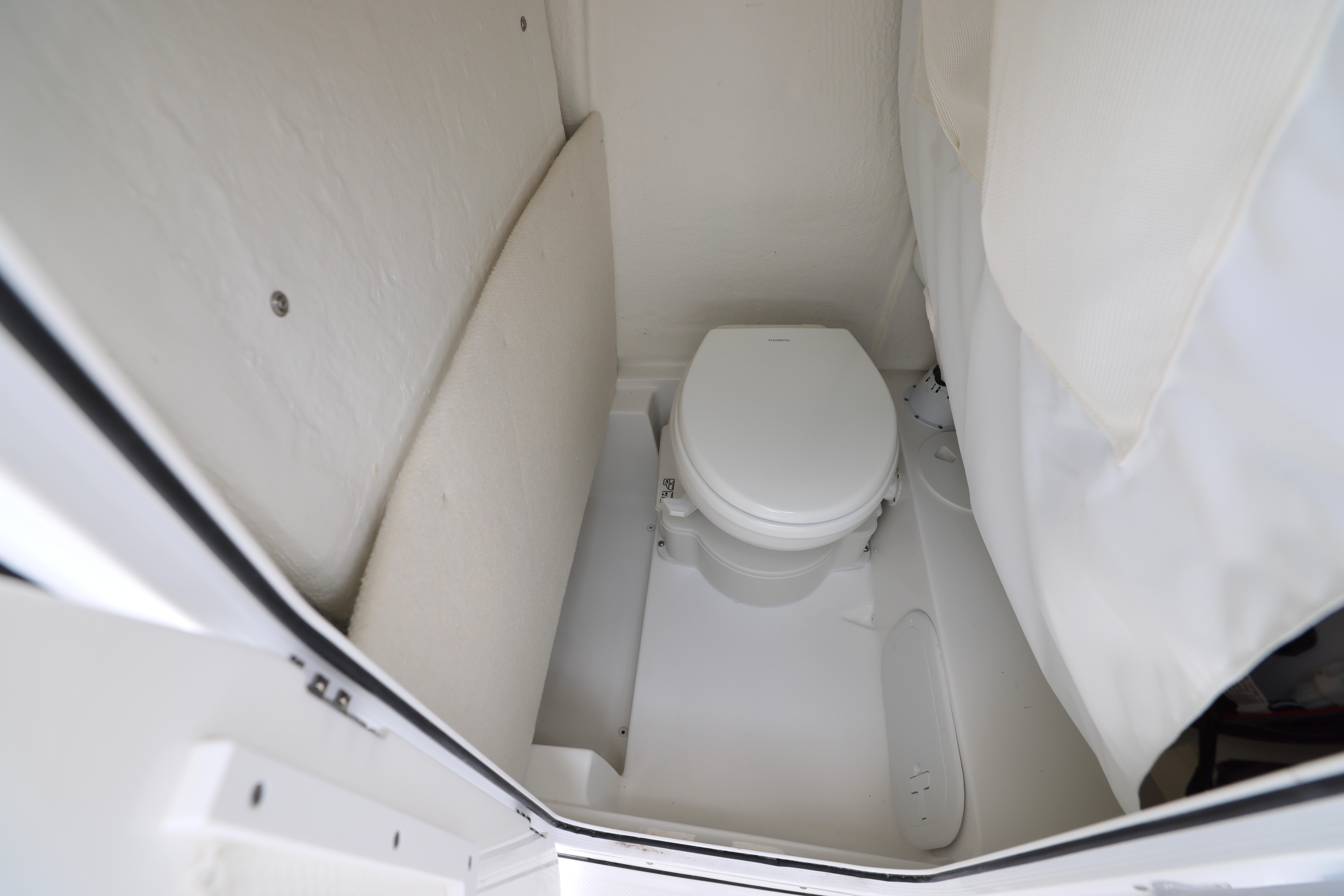 2026 Sea Hunt Ultra 245 SE boat interior with compact marine toilet.