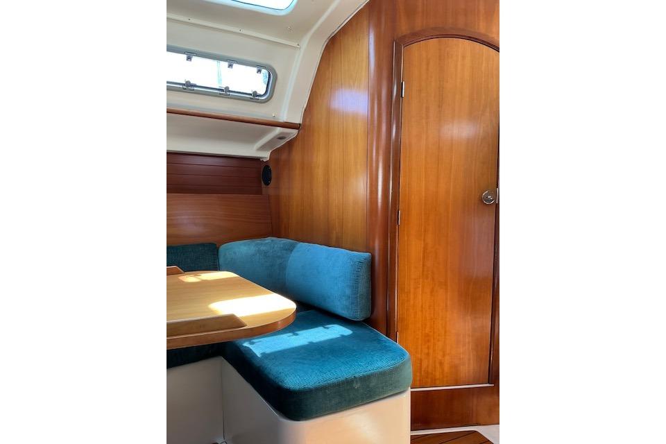 Interior of 2000 Beneteau Oceanis 321 sailboat with wooden paneling and blue cushioned seating.