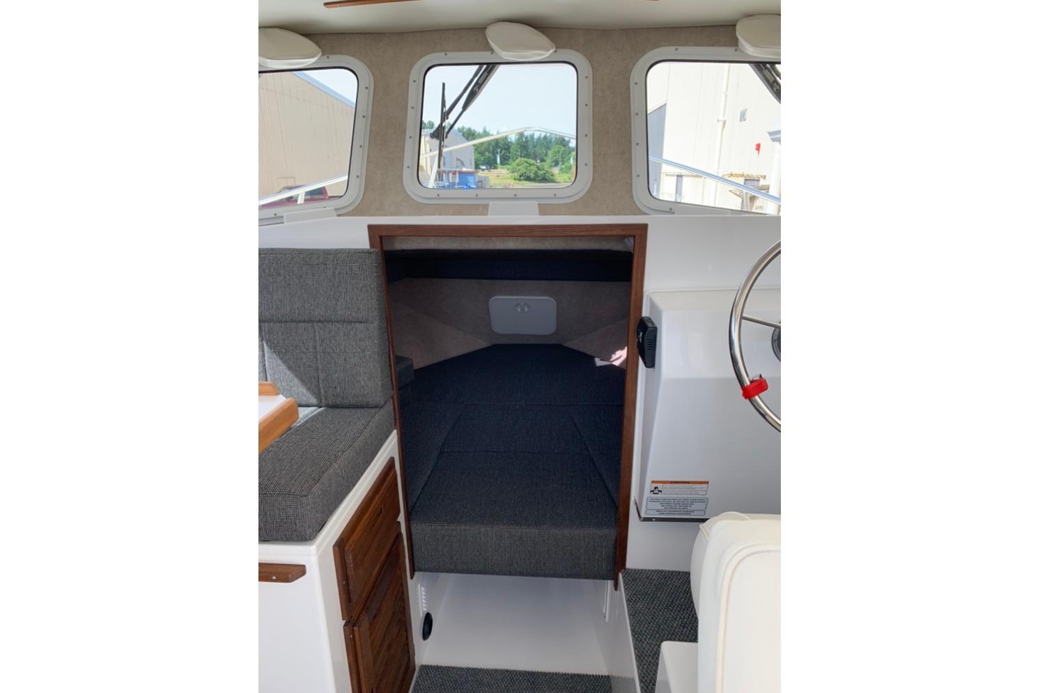 Interior cabin of 2026 Sea Sport Kenai 2600 boat, featuring seating and helm.