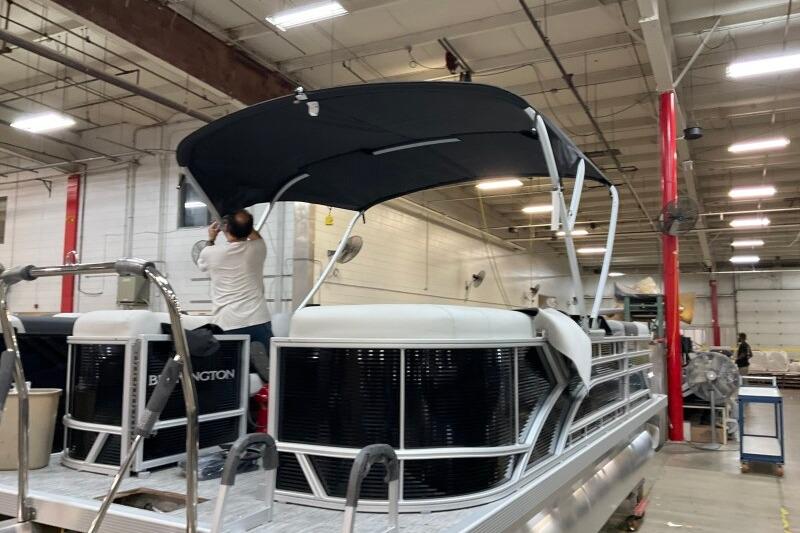 2026 Bennington 22 SSRSF pontoon boat in a warehouse, with a person adjusting the canopy.