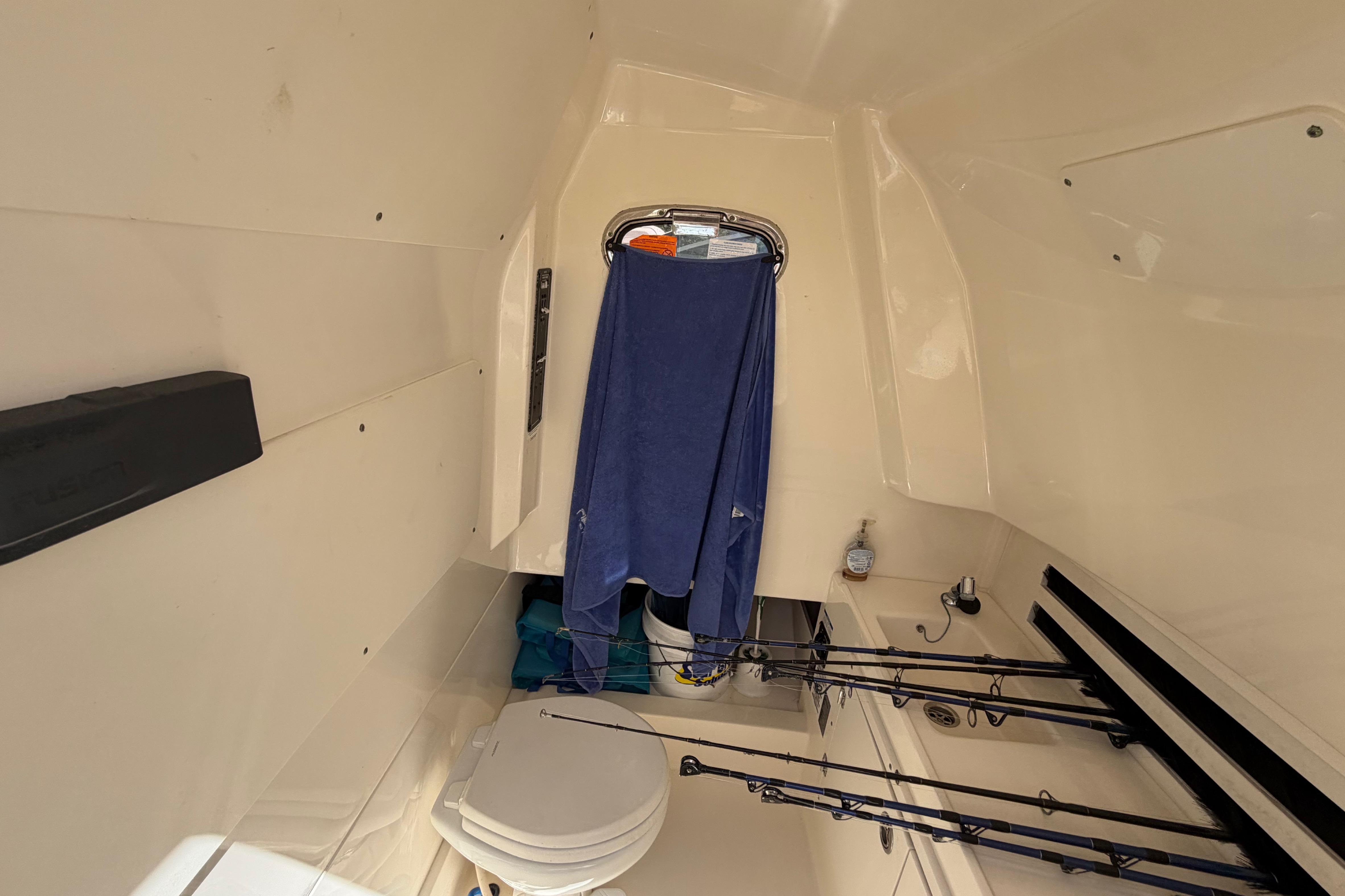 Interior cabin of 2019 Boston Whaler 330 Outrage with fishing rods and toilet.