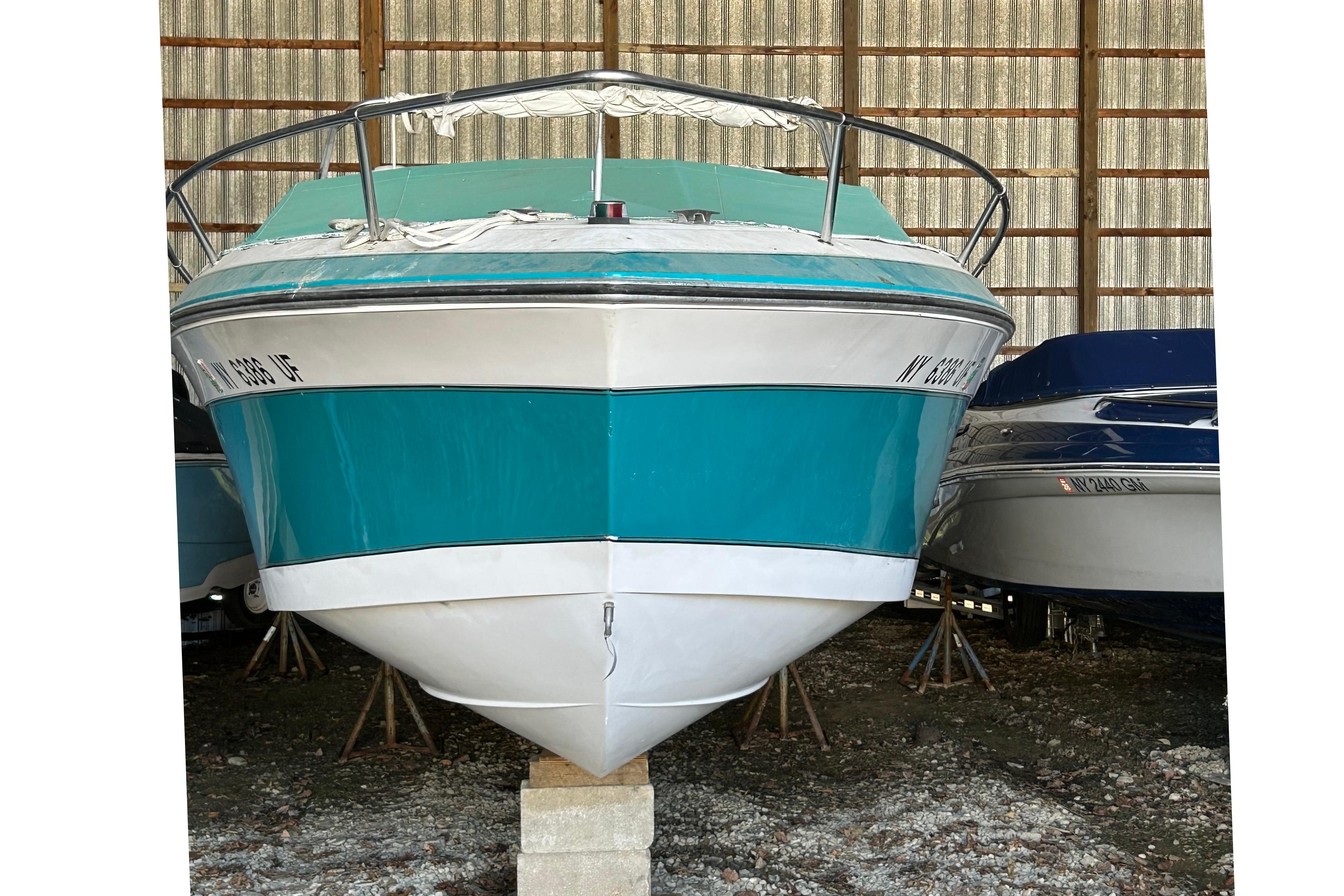 1991 Wellcraft 232 Eclipse boat in storage, teal and white exterior.