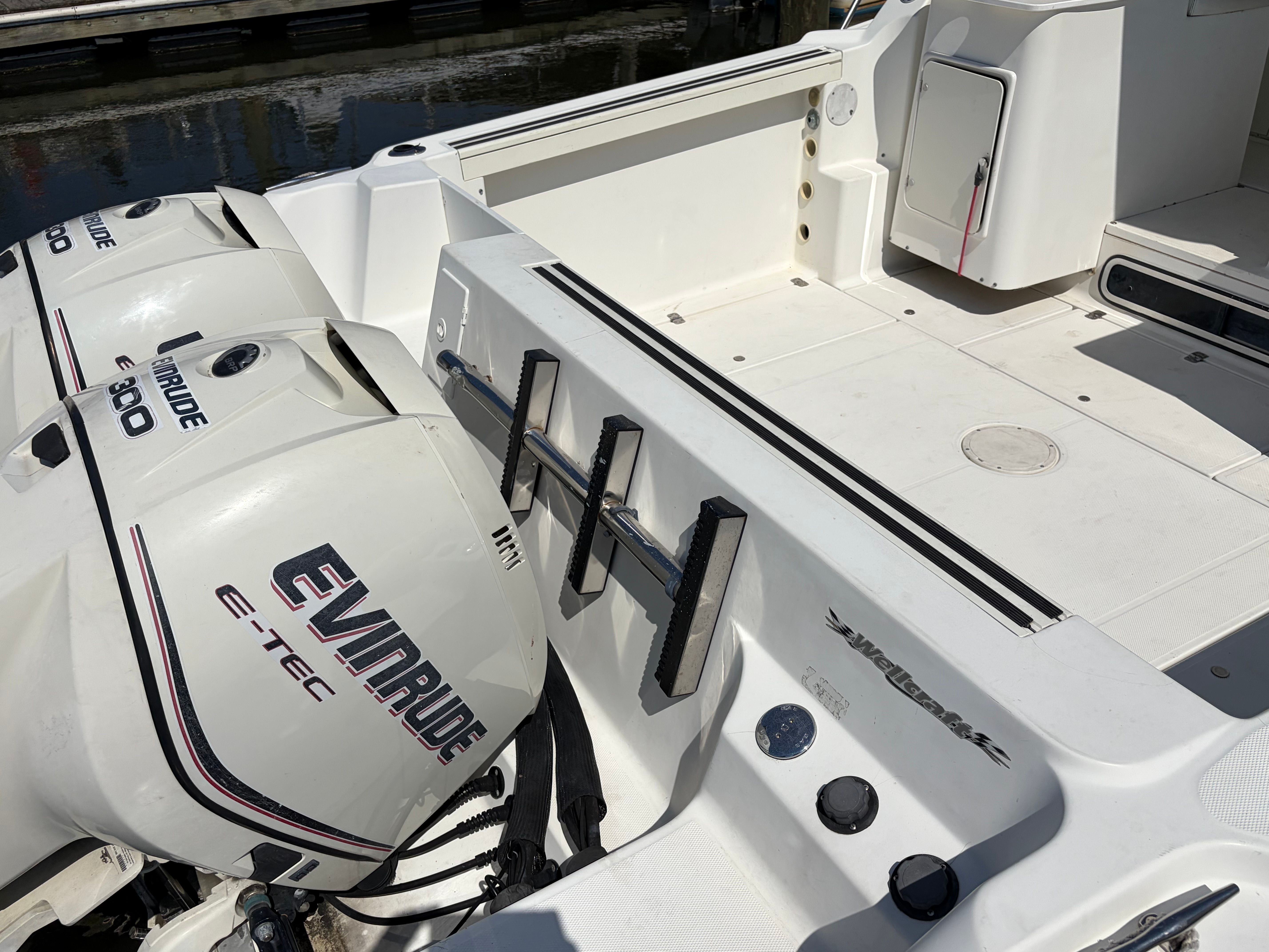The image shows the stern of a 2000 Wellcraft 290 Coastal boat with two Evinrude engines.