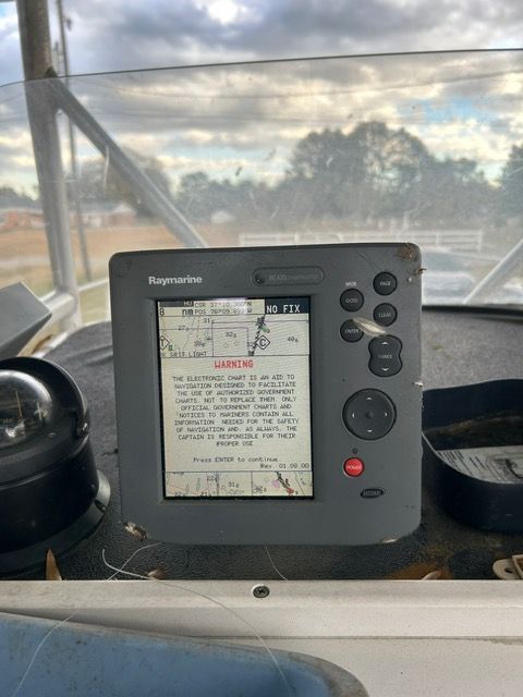 A Raymarine navigation device on a boat with a compass beside it.