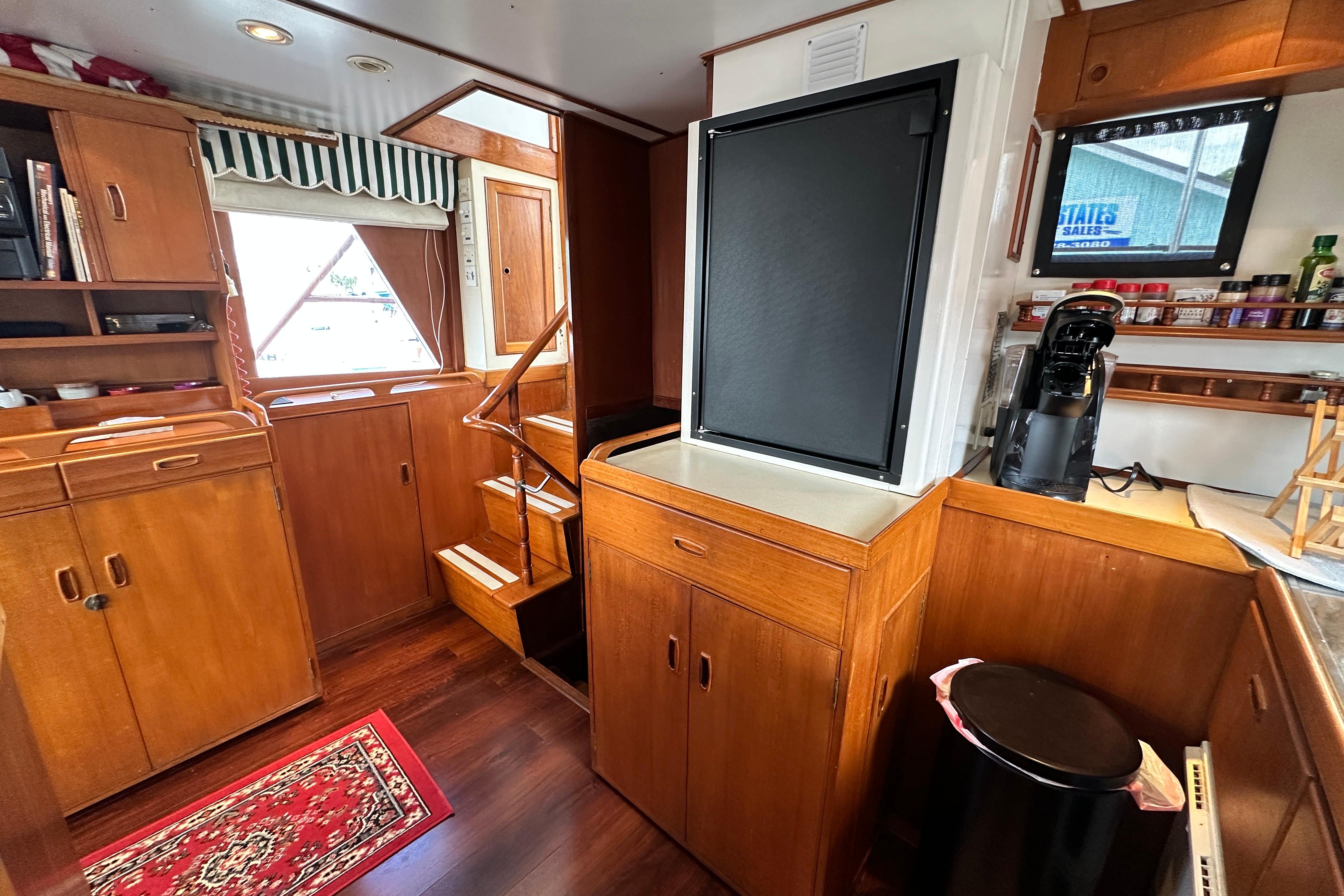 1980 Island Gypsy yacht interior with wooden cabinetry, stairs, and kitchen area.