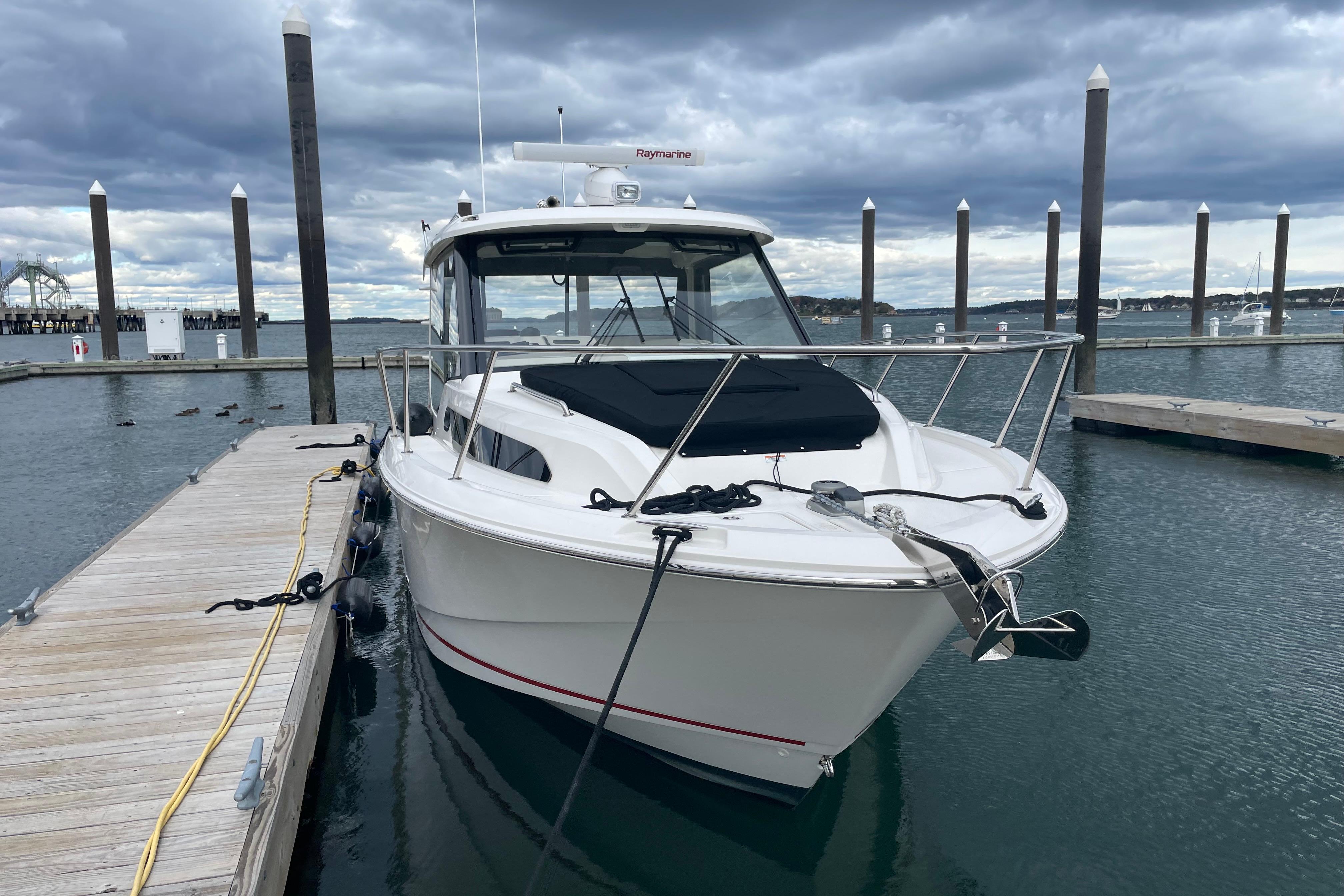 2023 Boston Whaler 325 Conquest docked at marina under cloudy sky.